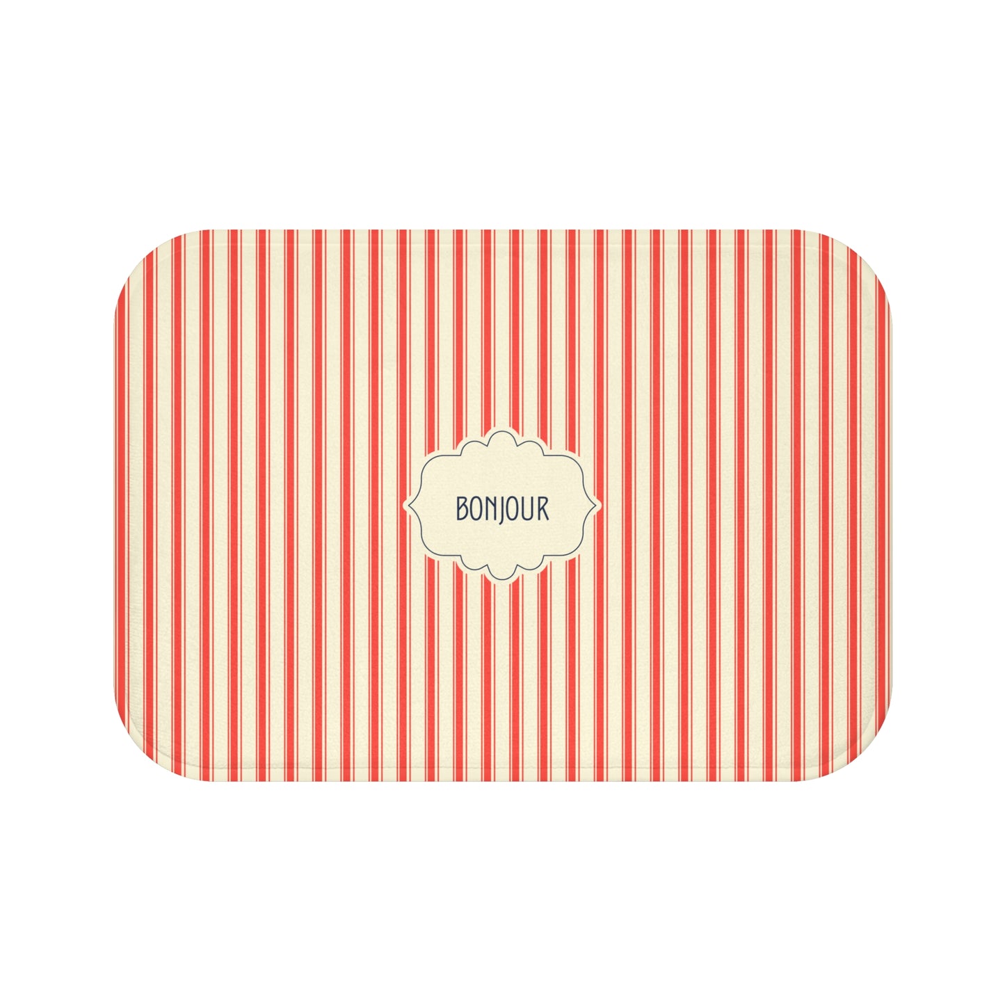 A bath mat with rounded corners, featuring a vertical red and white stripe pattern and a central cream-colored label that reads 'BONJOUR'.