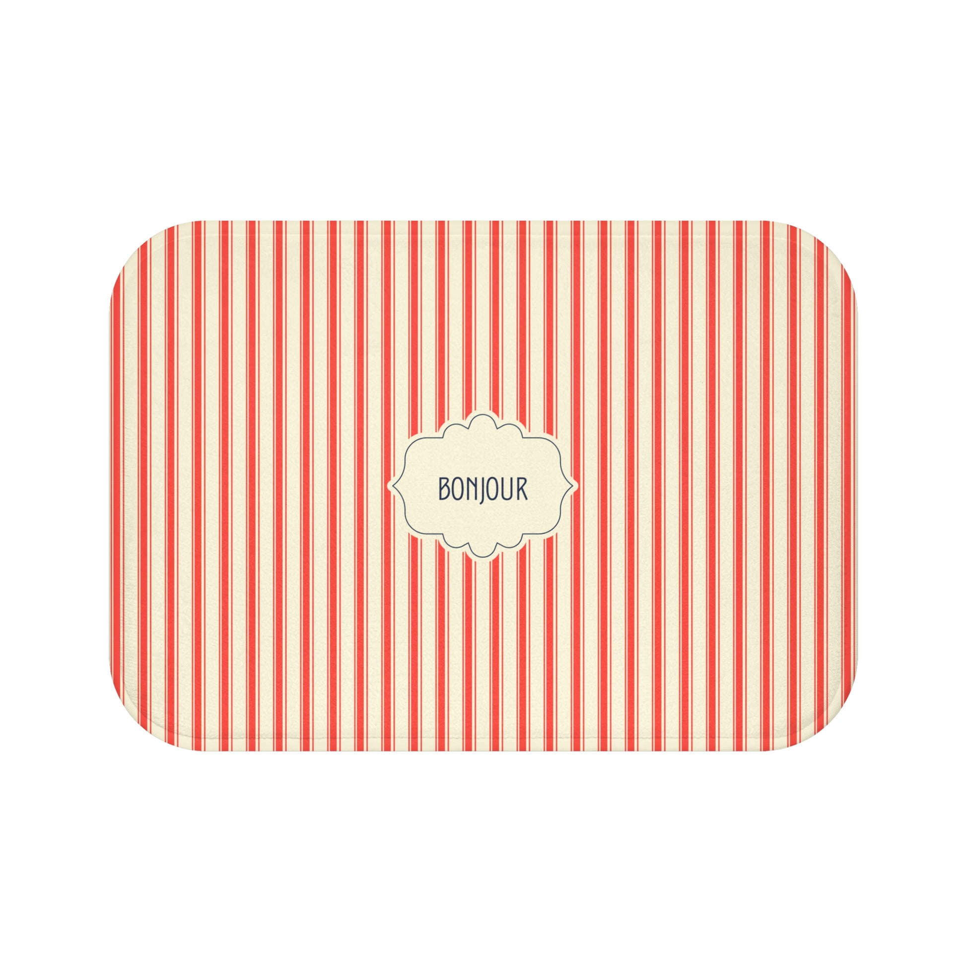 A bath mat with rounded corners, featuring a vertical red and white stripe pattern and a central cream-colored label that reads 'BONJOUR'.