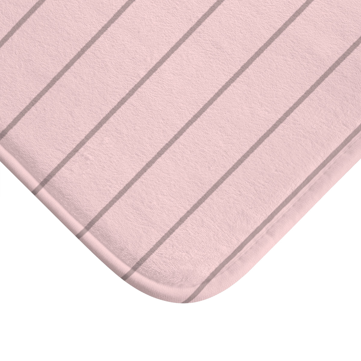 A close-up of a light pink bath mat with thin, evenly spaced dark gray vertical stripes, showing its soft texture and rounded corner on a white background.