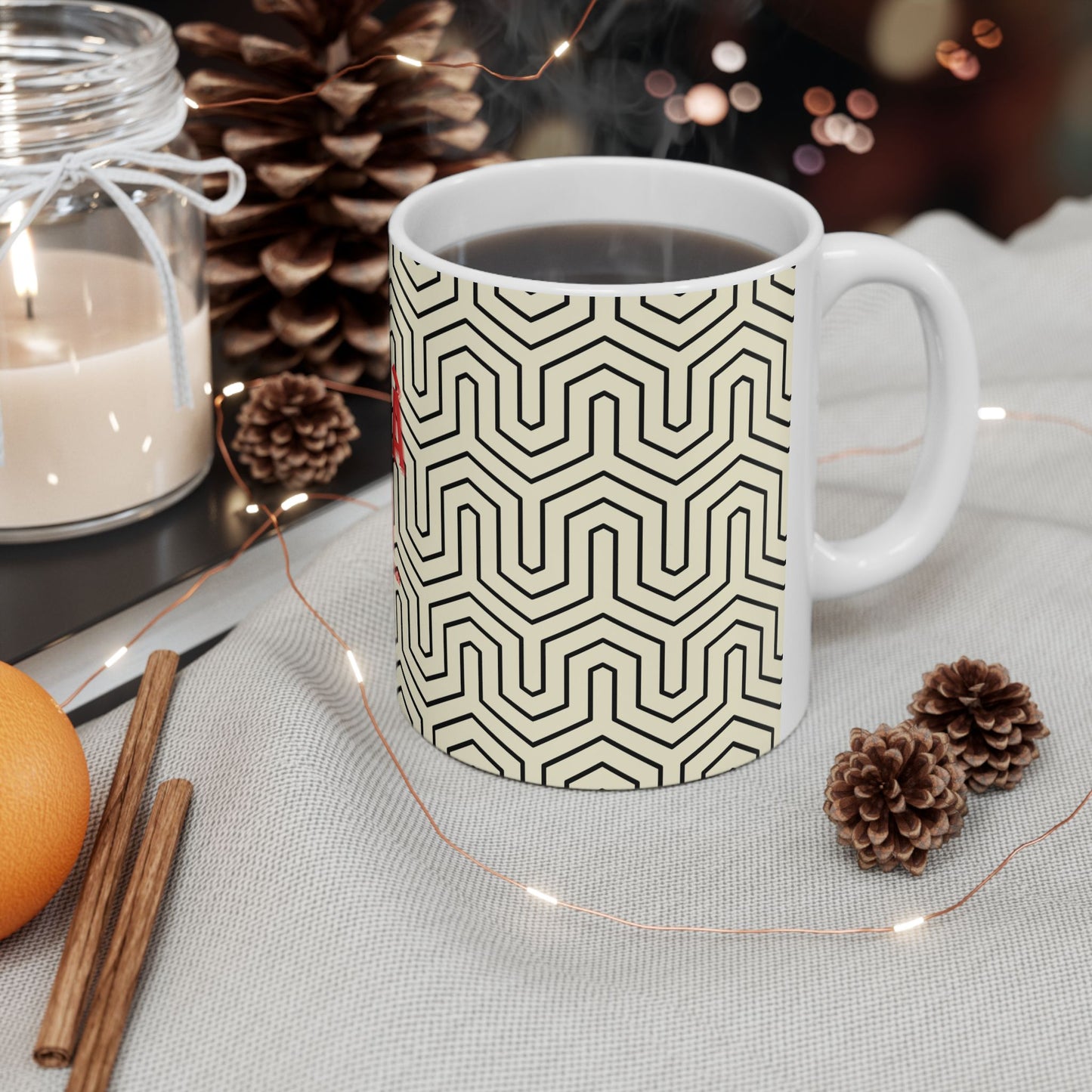 White mug with black geometric pattern on a table with decorative items