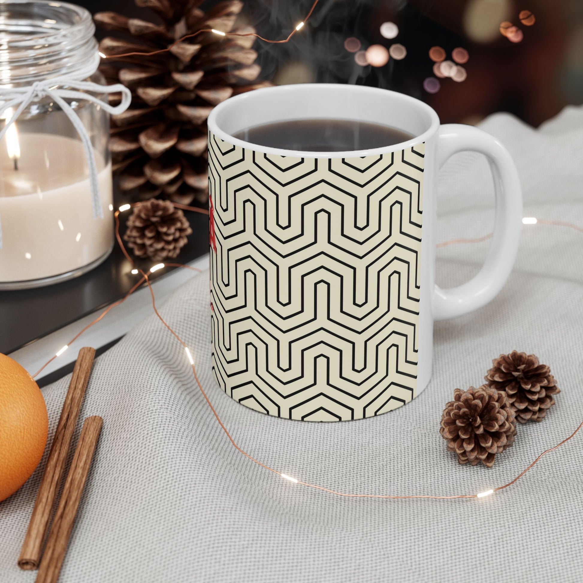 White mug with black geometric pattern on a table with decorative items