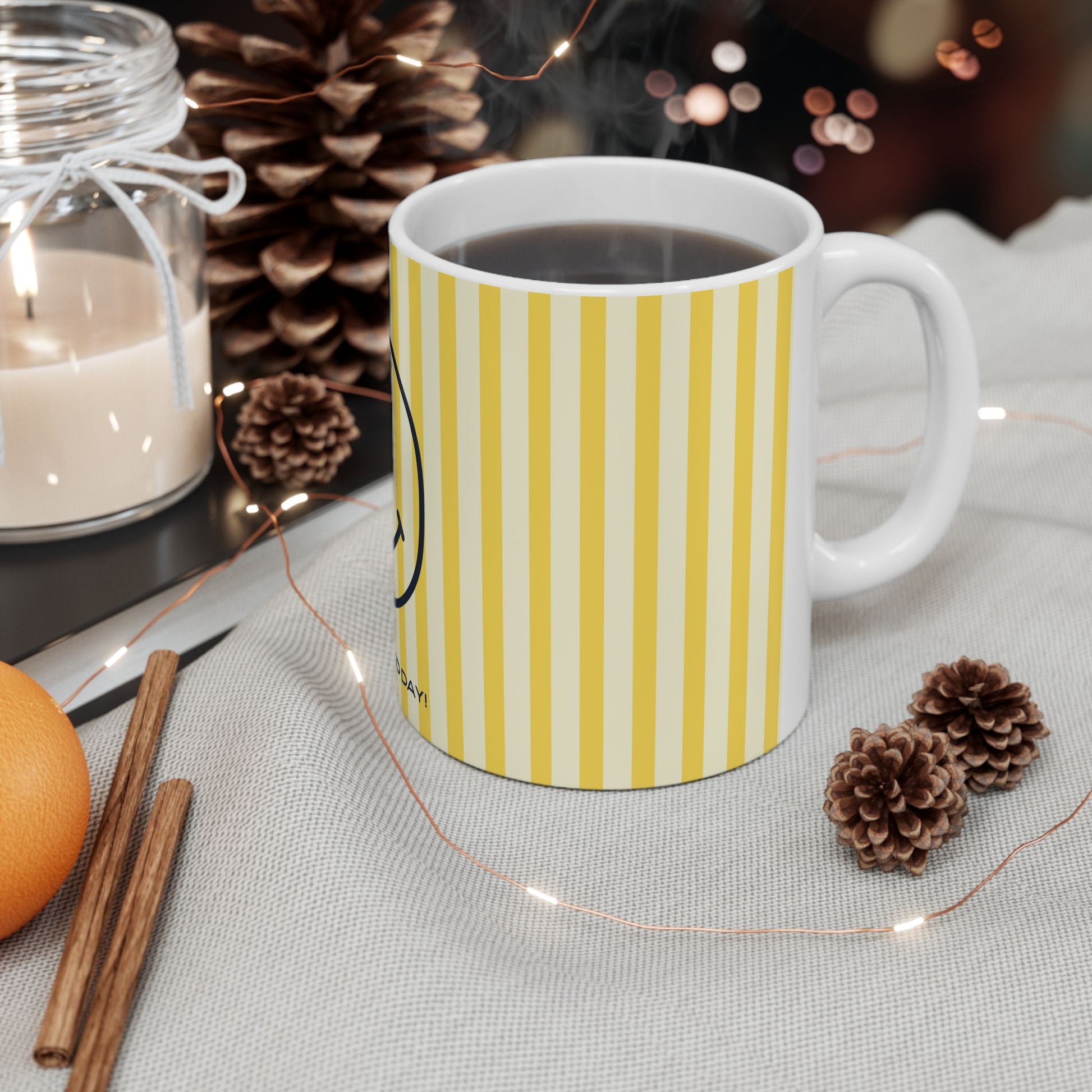 White mug with yellow stripes on a table with decorative items