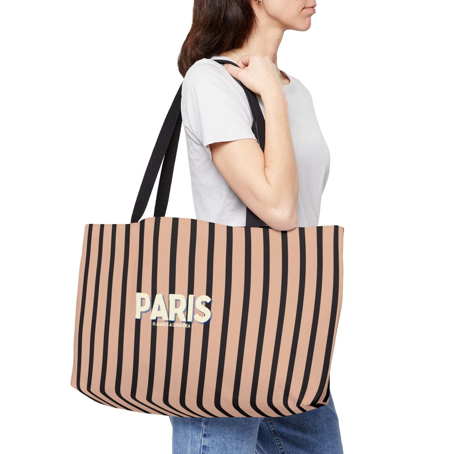 Person holding a striped tote bag with 'PARIS' text on a white background