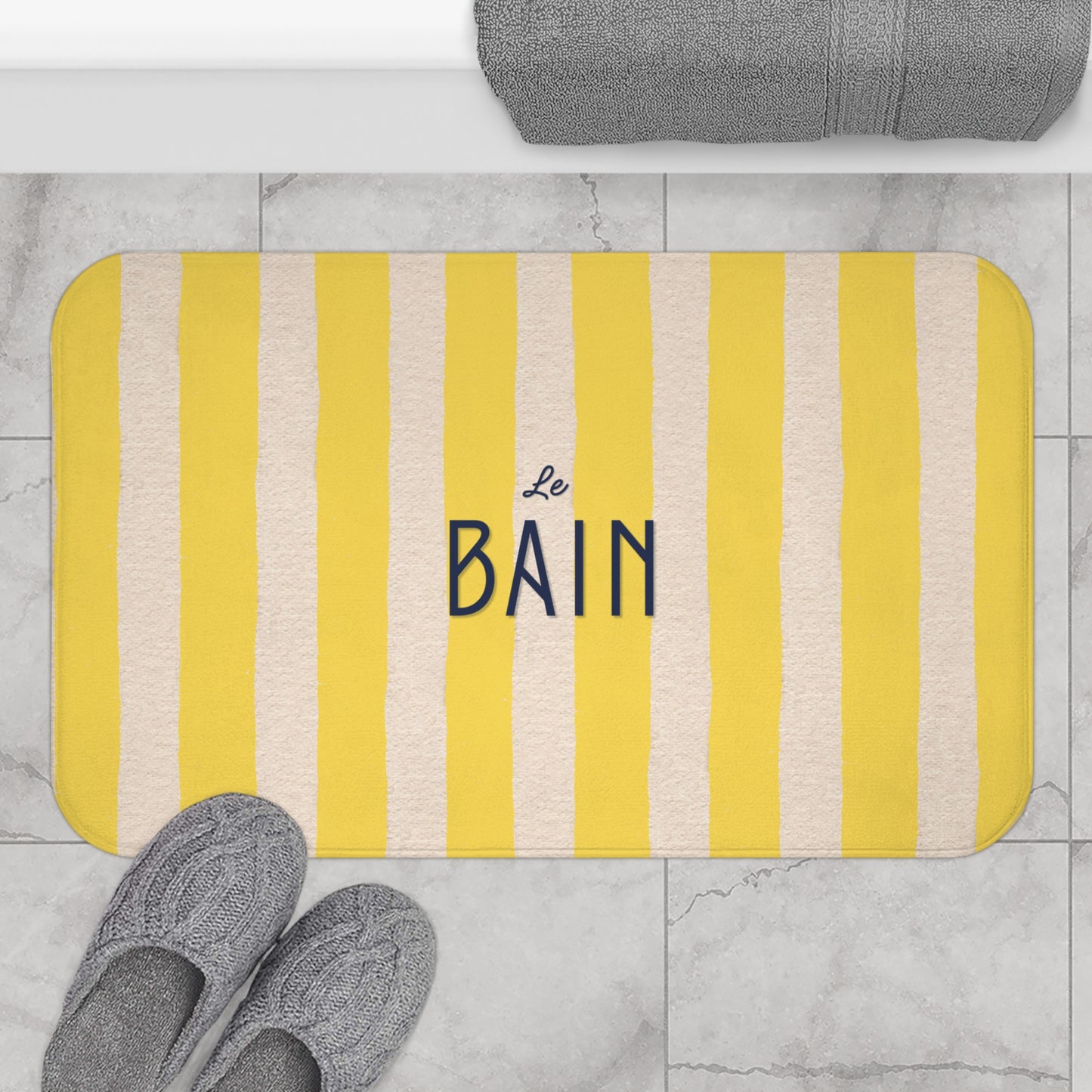 Striped bath mat with 'Le Bain' text on a bathroom floor.