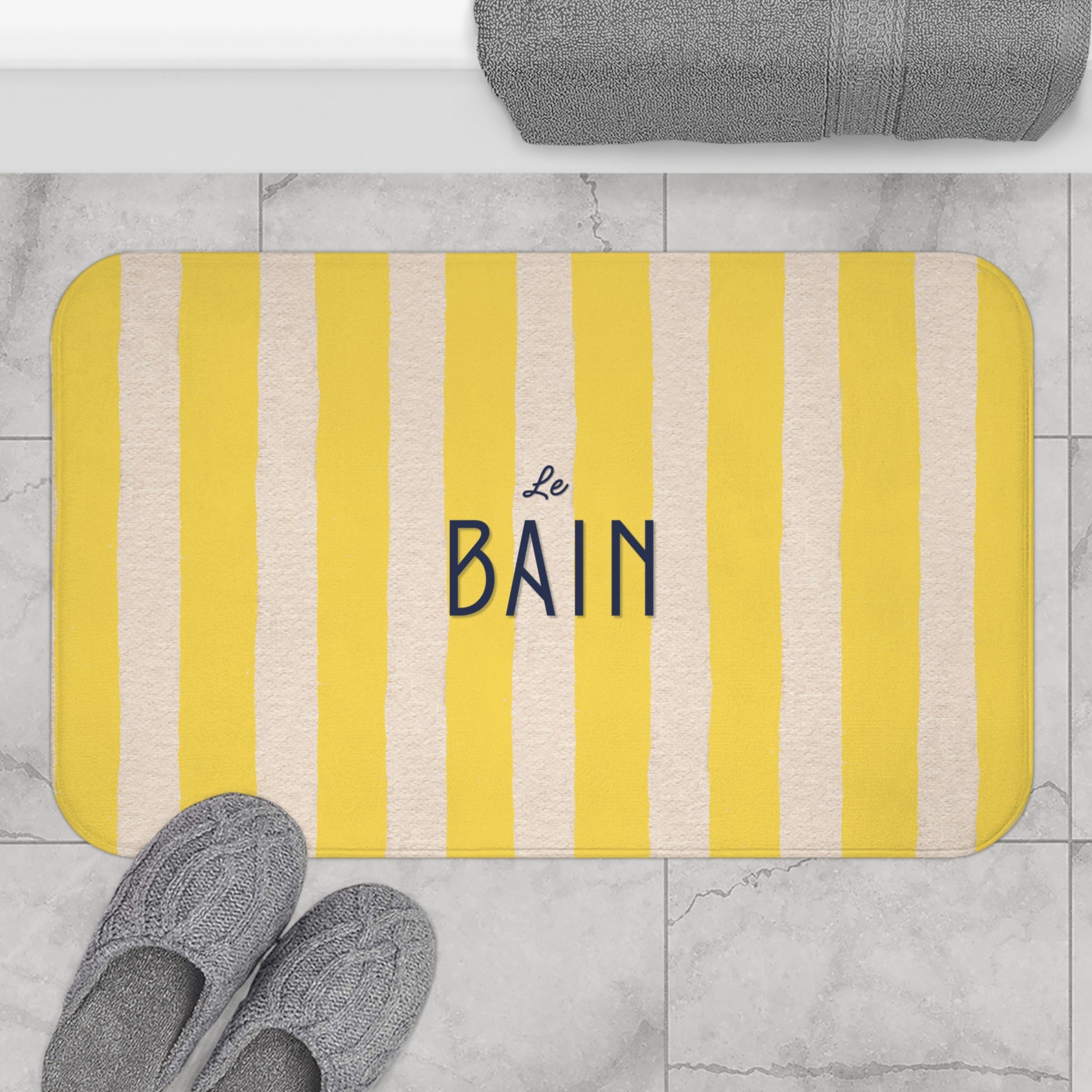 Striped bath mat with 'Le Bain' text on a bathroom floor.