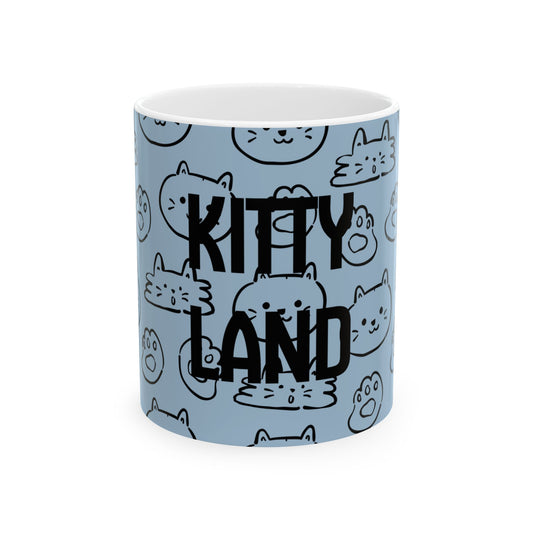 A light blue ceramic mug with a white interior, featuring a repeating pattern of black-and-white cartoon cat faces and the words 'KITTY LAND' in large black letters across the front.