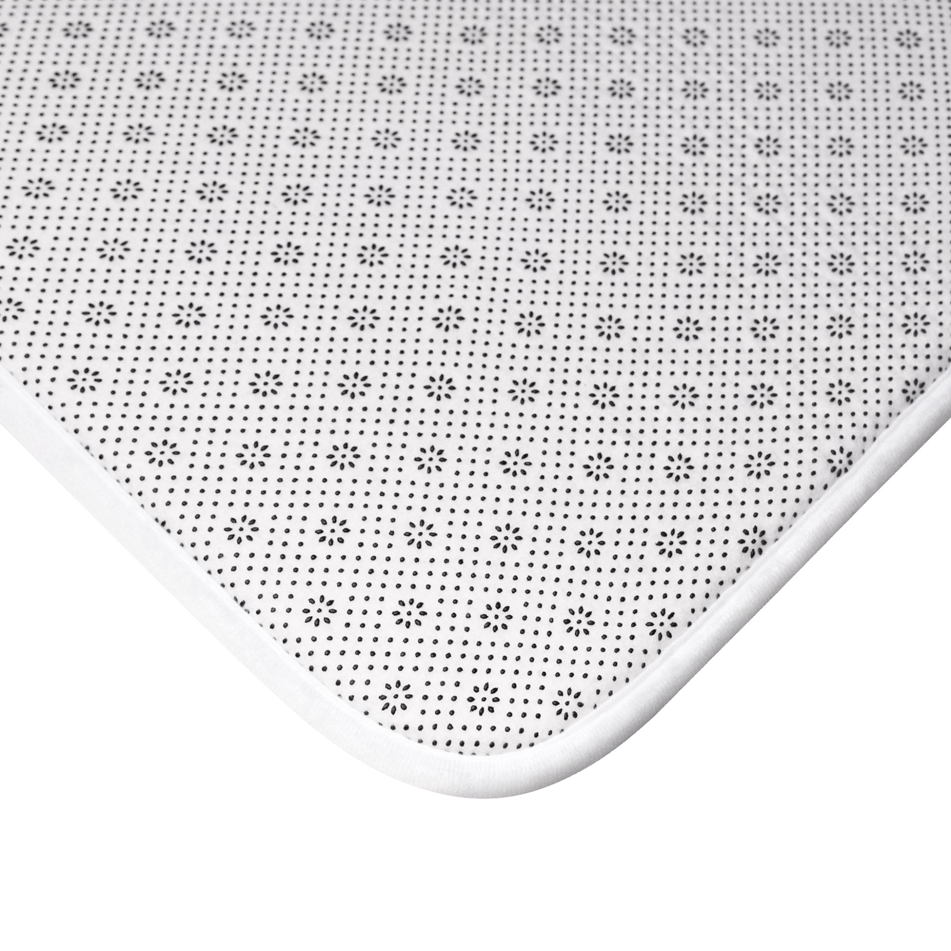 White bath mat with black floral pattern on a white background