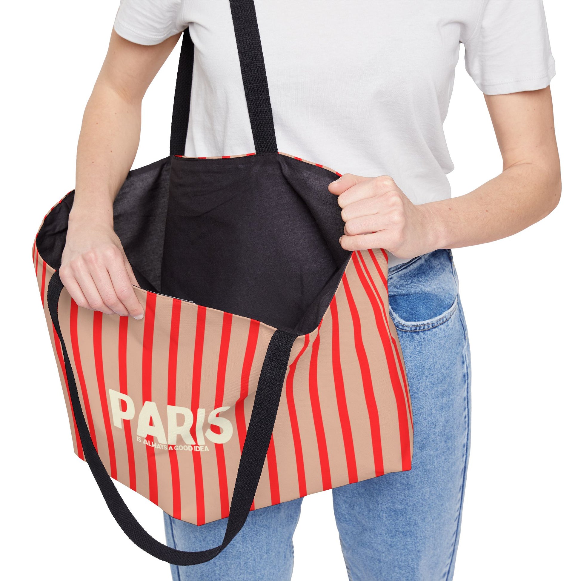 Person holding a striped bag with 'PARIS' text on a white background