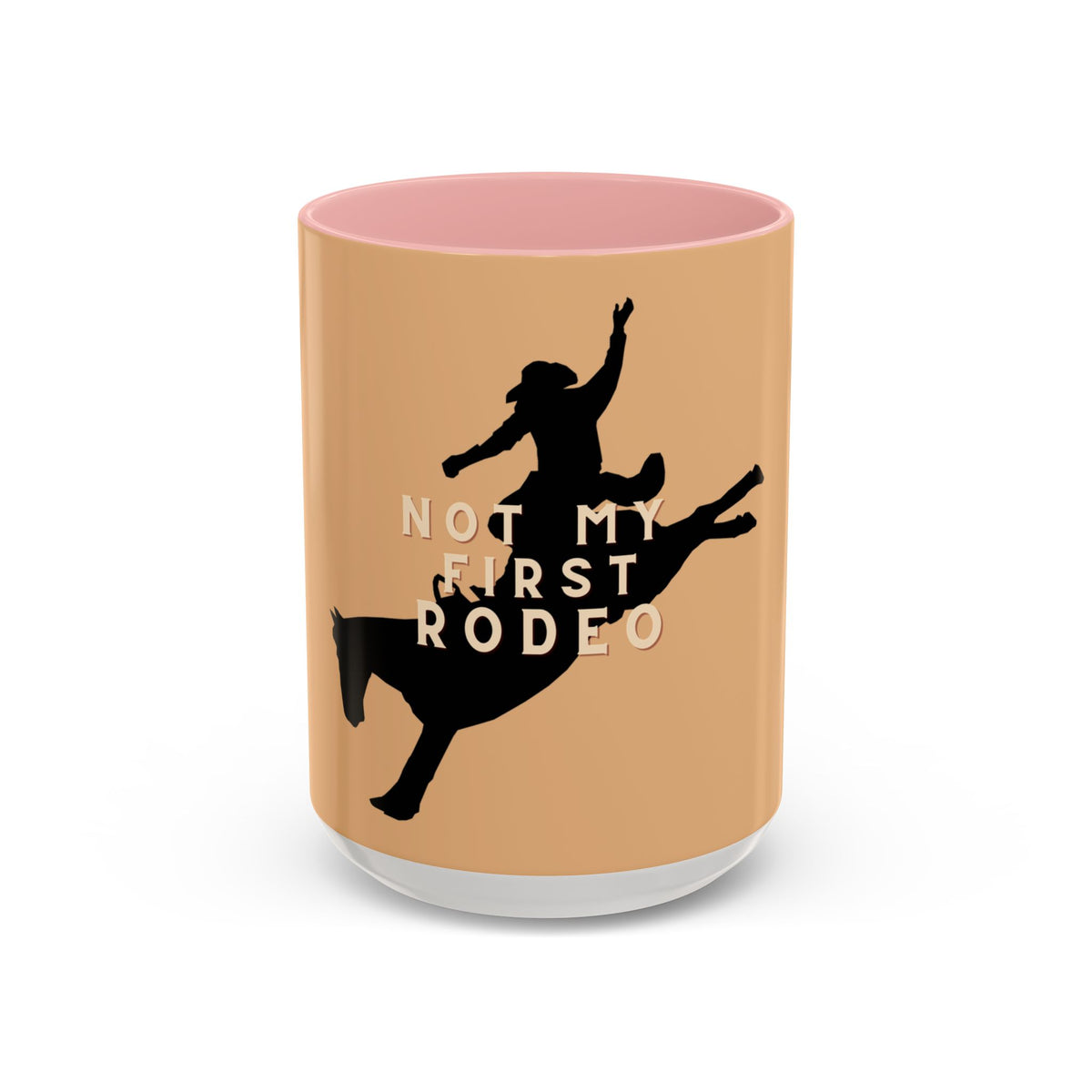 A ceramic mug with a peach-colored exterior, a pink interior, and a white base, featuring a black silhouette of a rider on a horse with the text 'NOT MY FIRST RODEO'.