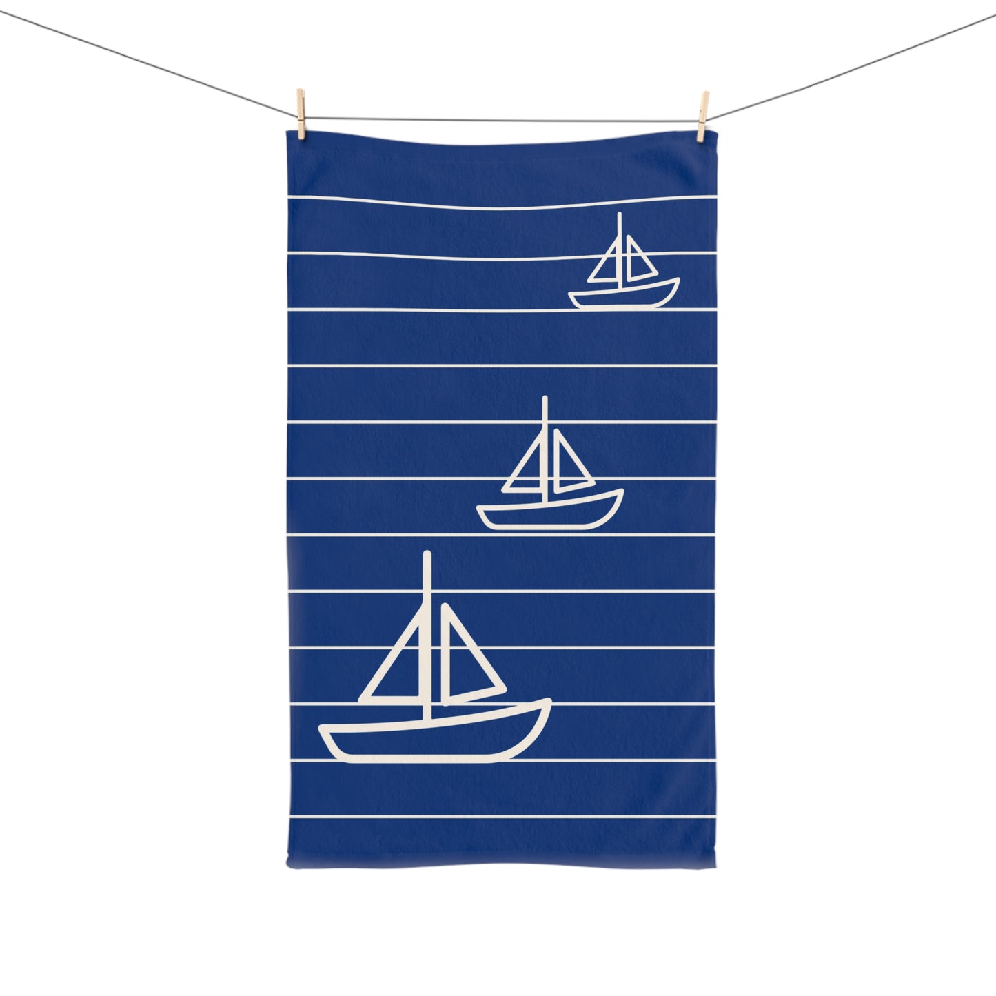Navy blue towel with white sailboat pattern hanging on a line.