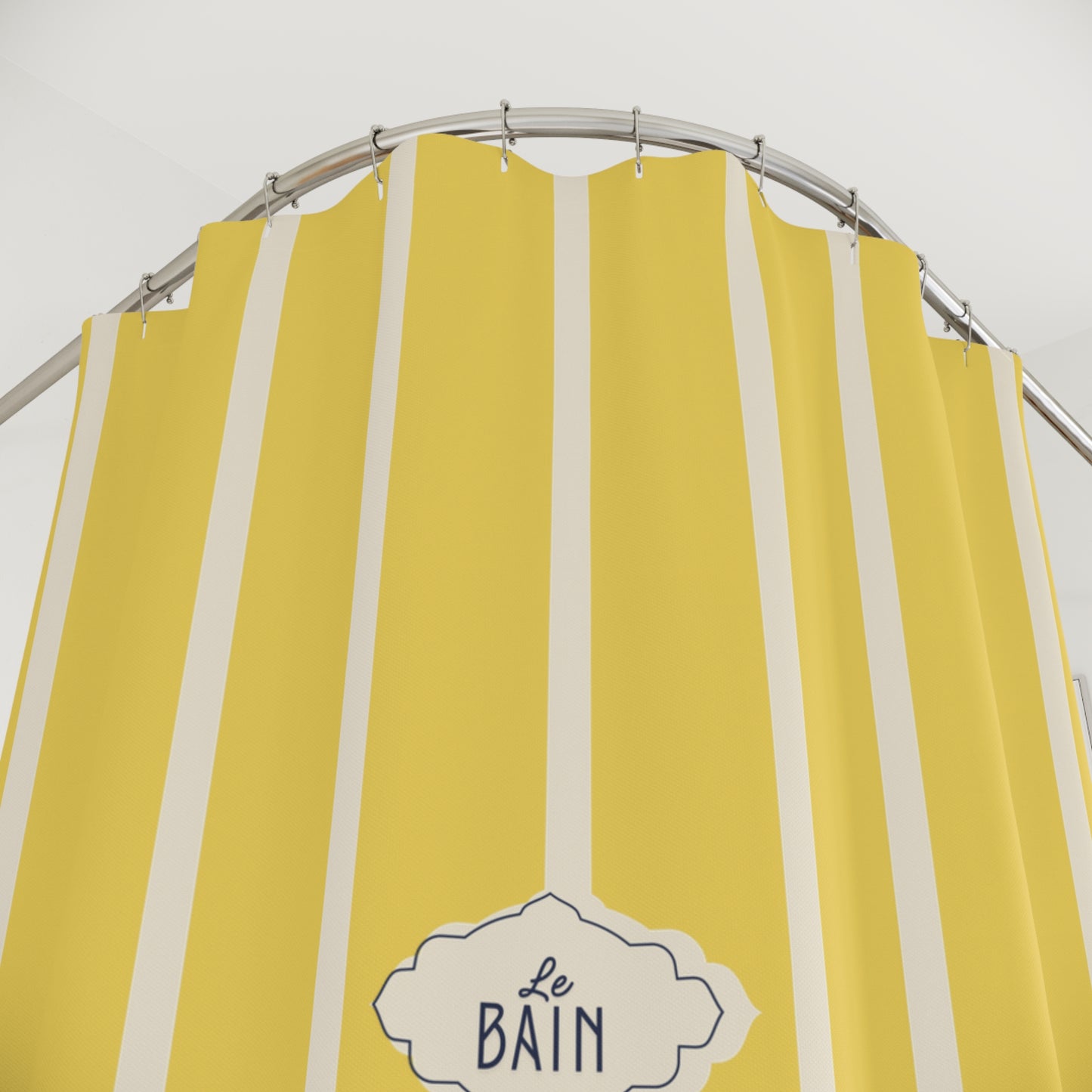 Yellow and white vertically striped shower curtain with a metal curved rod and a decorative label reading 'Le Bain'.