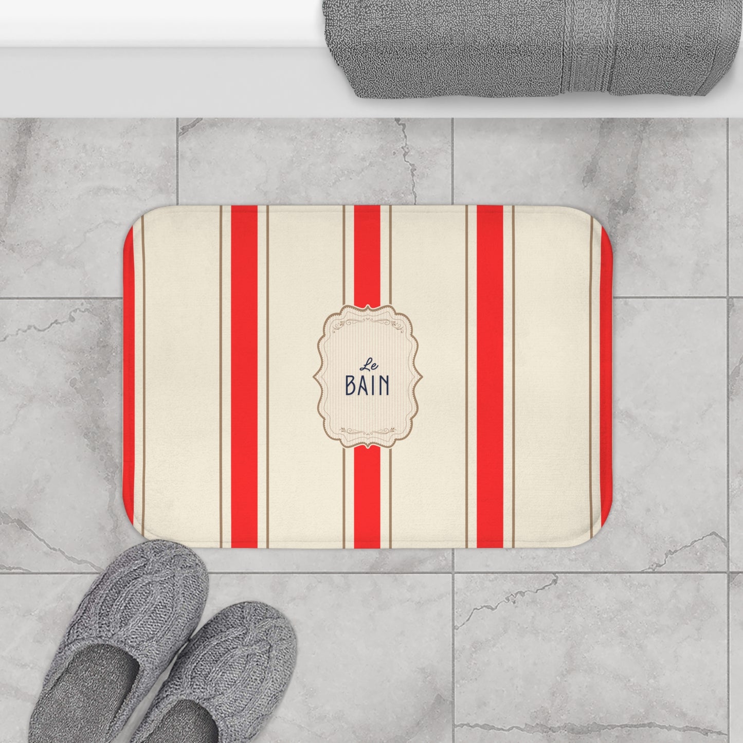 Striped bath mat with 'Le Bain' text on a tiled bathroom floor.
