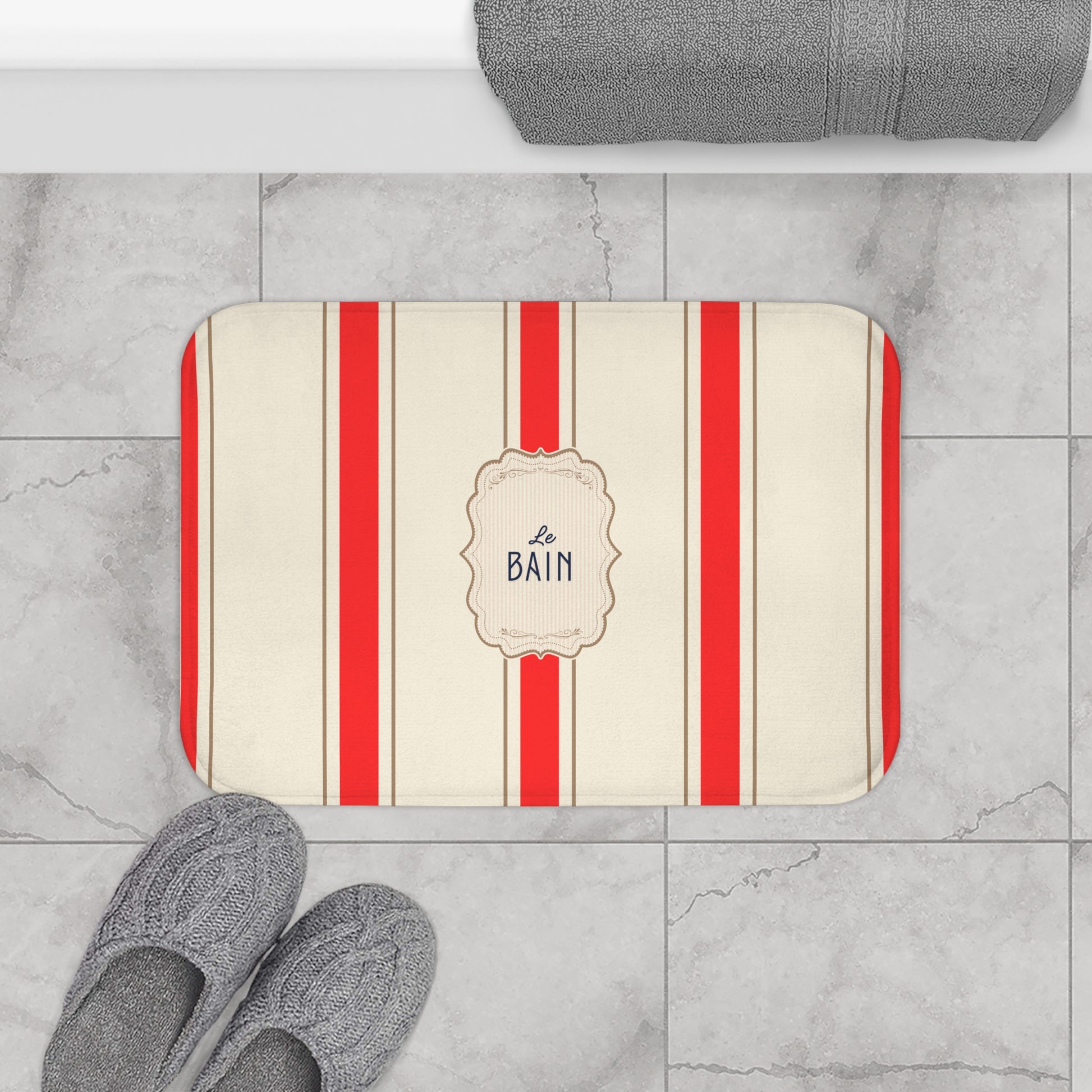 Striped bath mat with 'Le Bain' text on a tiled bathroom floor.