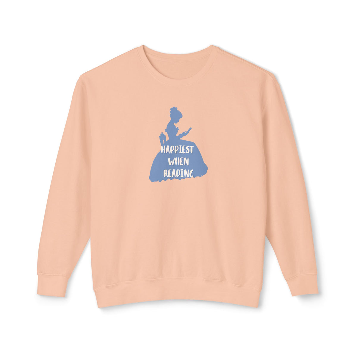 A peach-colored crewneck sweatshirt featuring a blue graphic of a woman in a book, with the text 'HAPPIEST WHEN READING' printed on the front, displayed against a solid white background.
