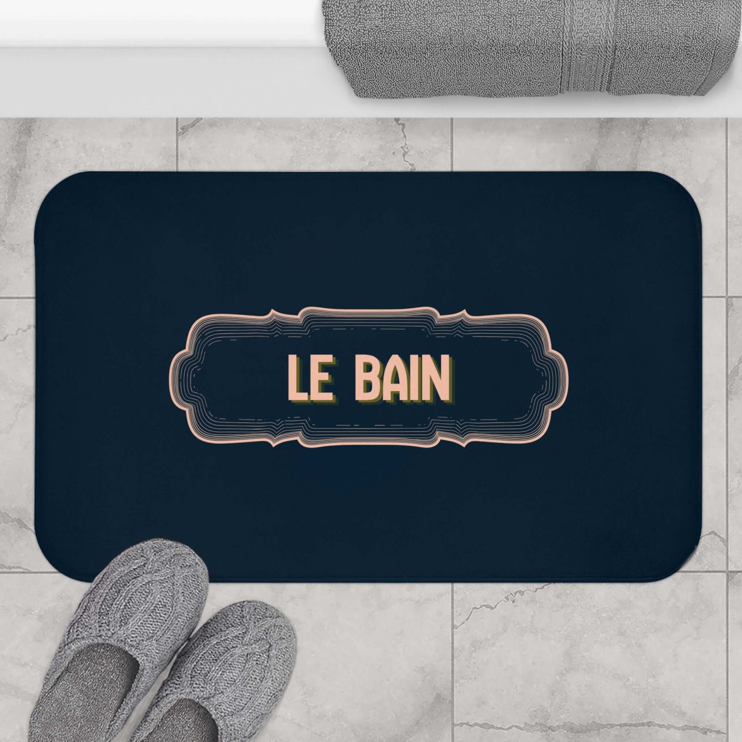 Navy bath mat with 'LE BAIN' text on a marble floor.