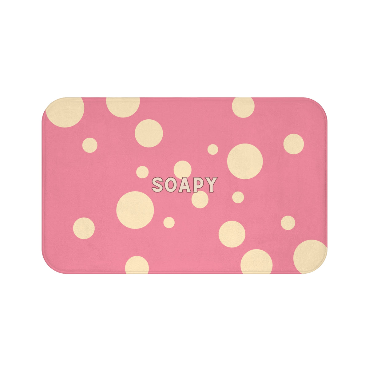 A rectangular bath mat with rounded corners, featuring a pink background with scattered beige polka dots and the word 'SOAPY' printed in the center.