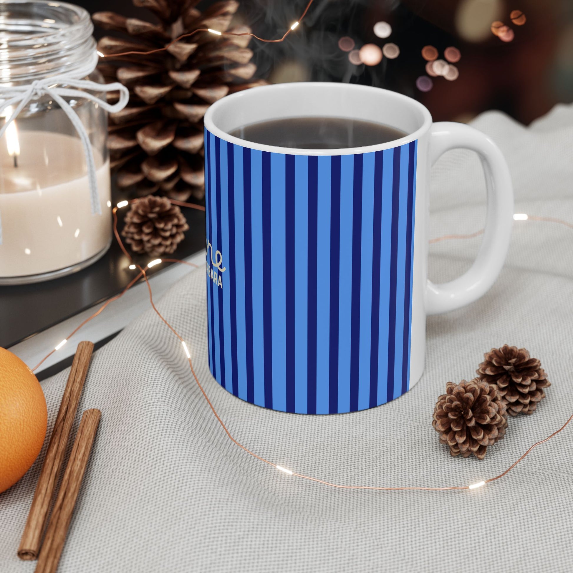 Blue mug with heart pattern on a table with candles and pinecones