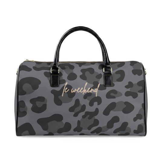 A gray and black leopard print duffle bag with black handles and gold-tone hardware, featuring the script text 'le weekend' in gold on the front.