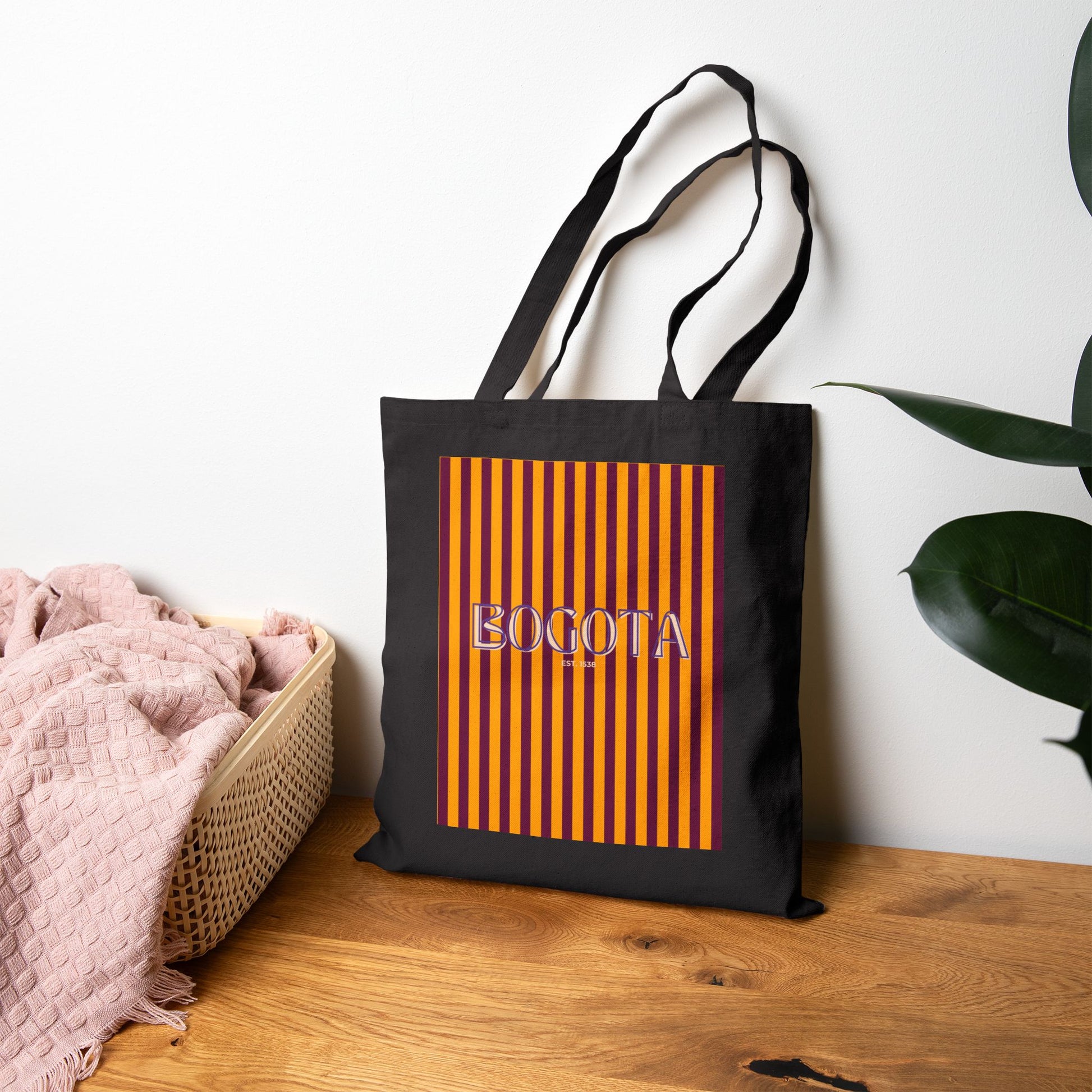 Black tote bag with orange stripes and 'BOGOTA' text on a wooden surface.