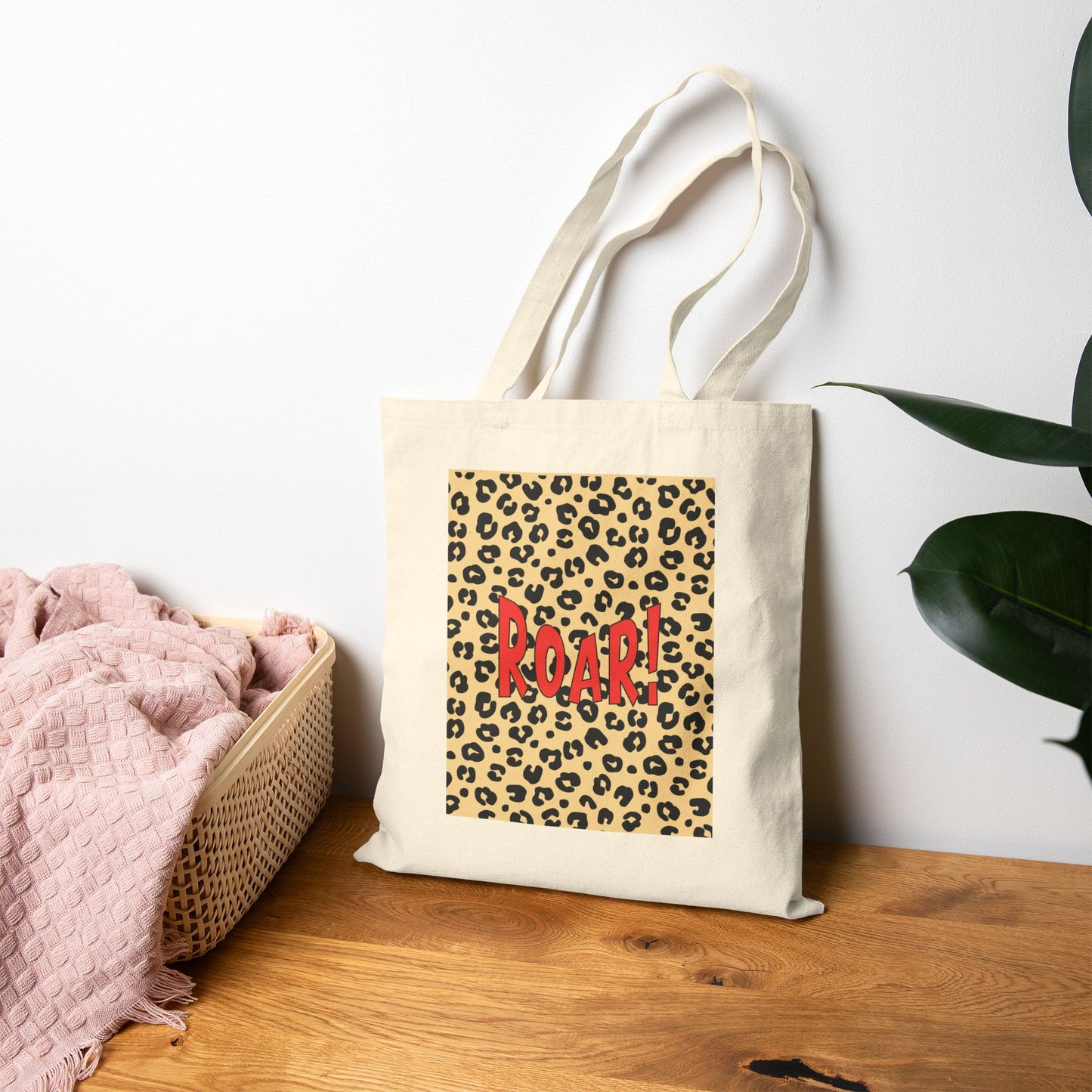 Tote bag with leopard print and 'ROAR!' text on a wooden surface with a white wall background.
