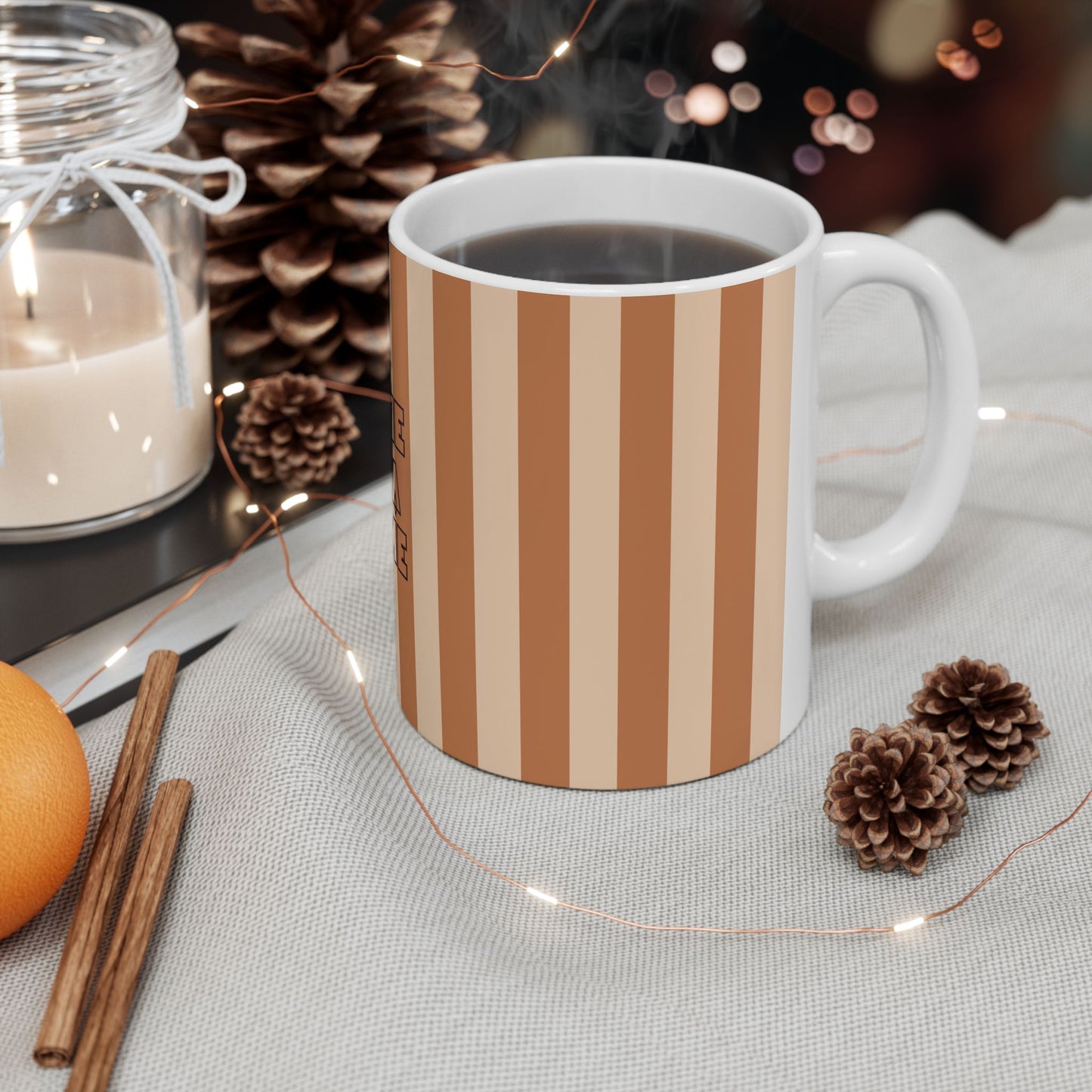 Mug with floral pattern on a table with candles, oranges, and pine cones.