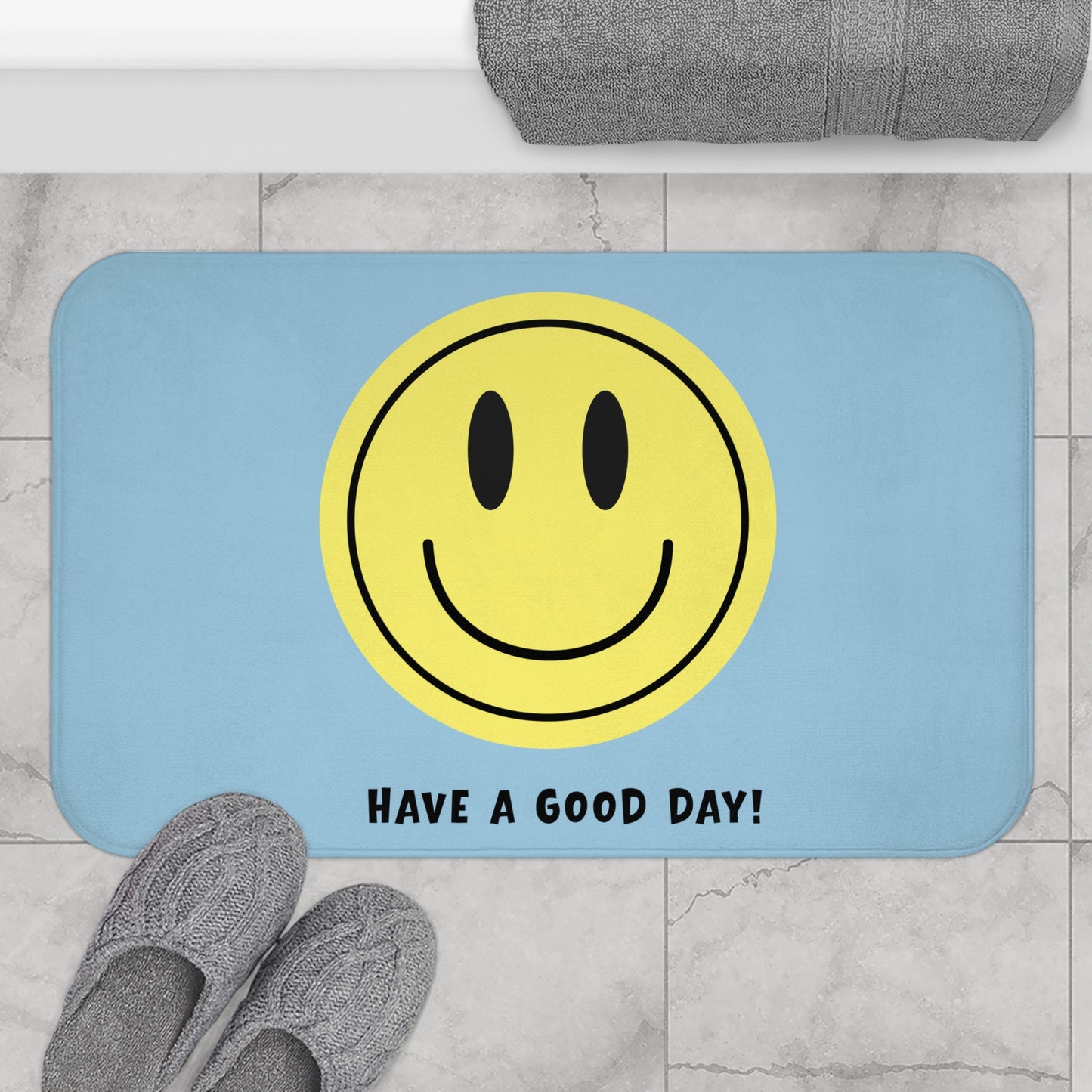 Bath mat with smiley face and 'Have a Good Day!' text on a bathroom floor.