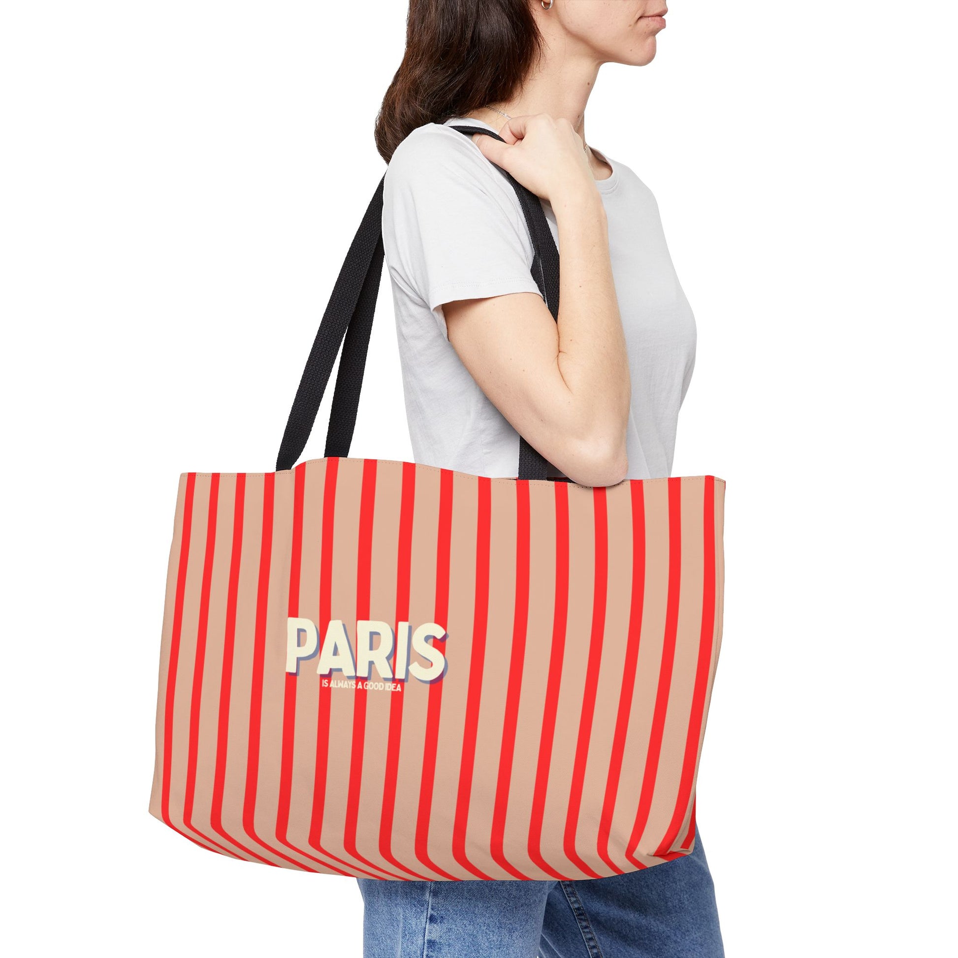 Person holding a red and beige striped bag with 'PARIS' text on a white background