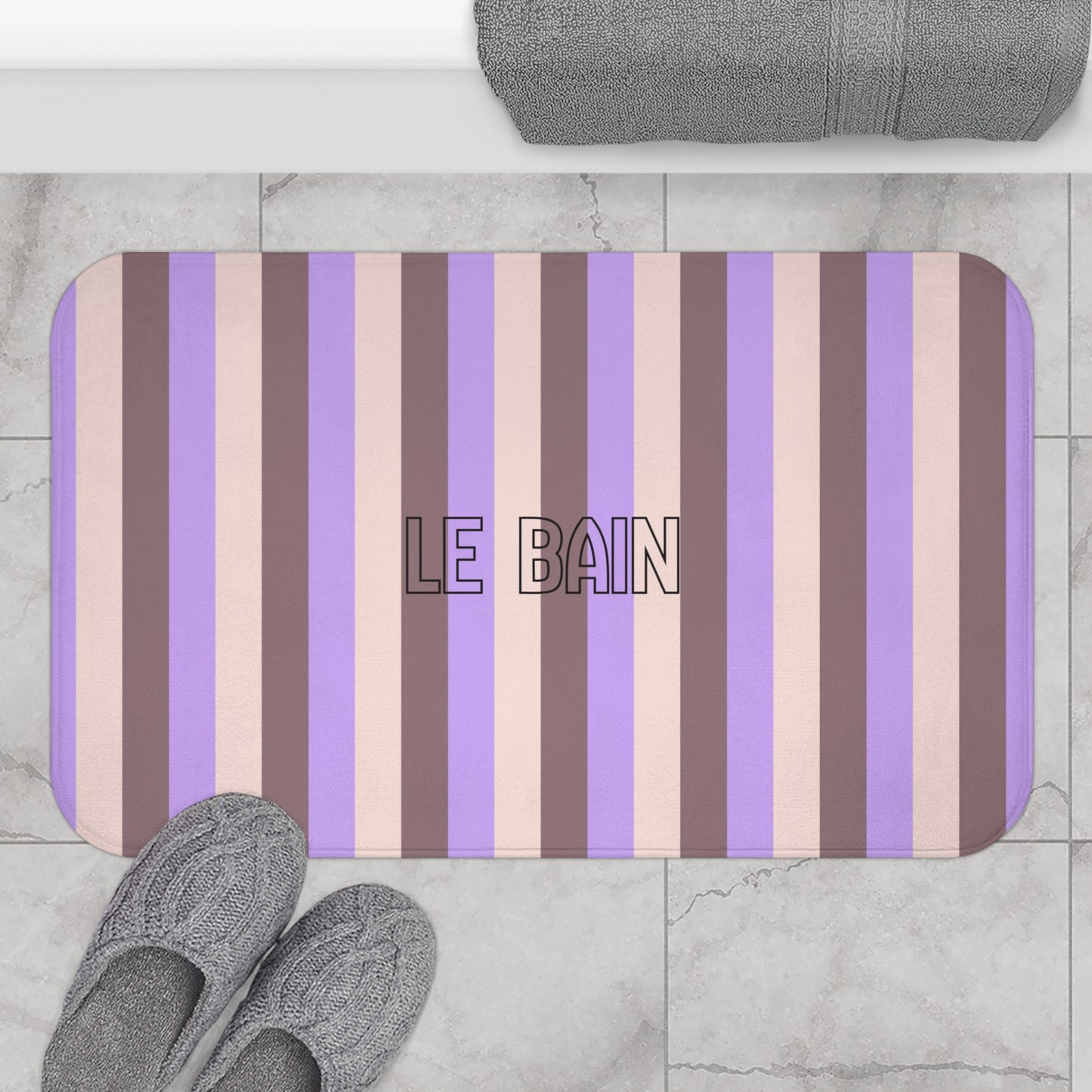Striped bath mat with 'LE BAIN' text on a marble floor.