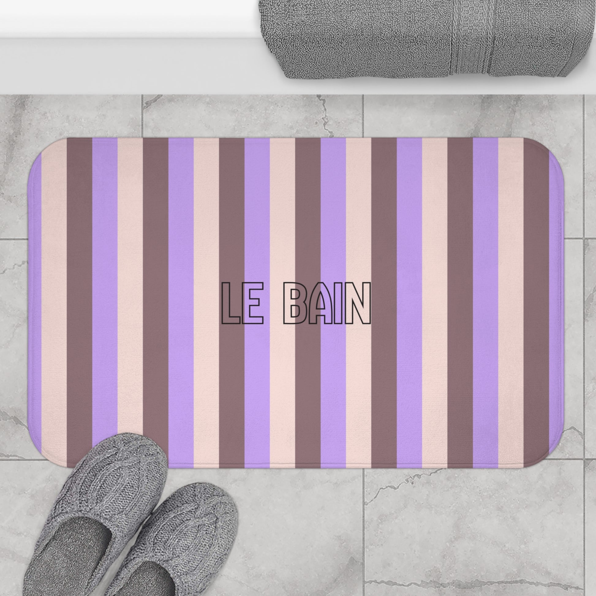 Striped bath mat with 'LE BAIN' text on a marble floor.