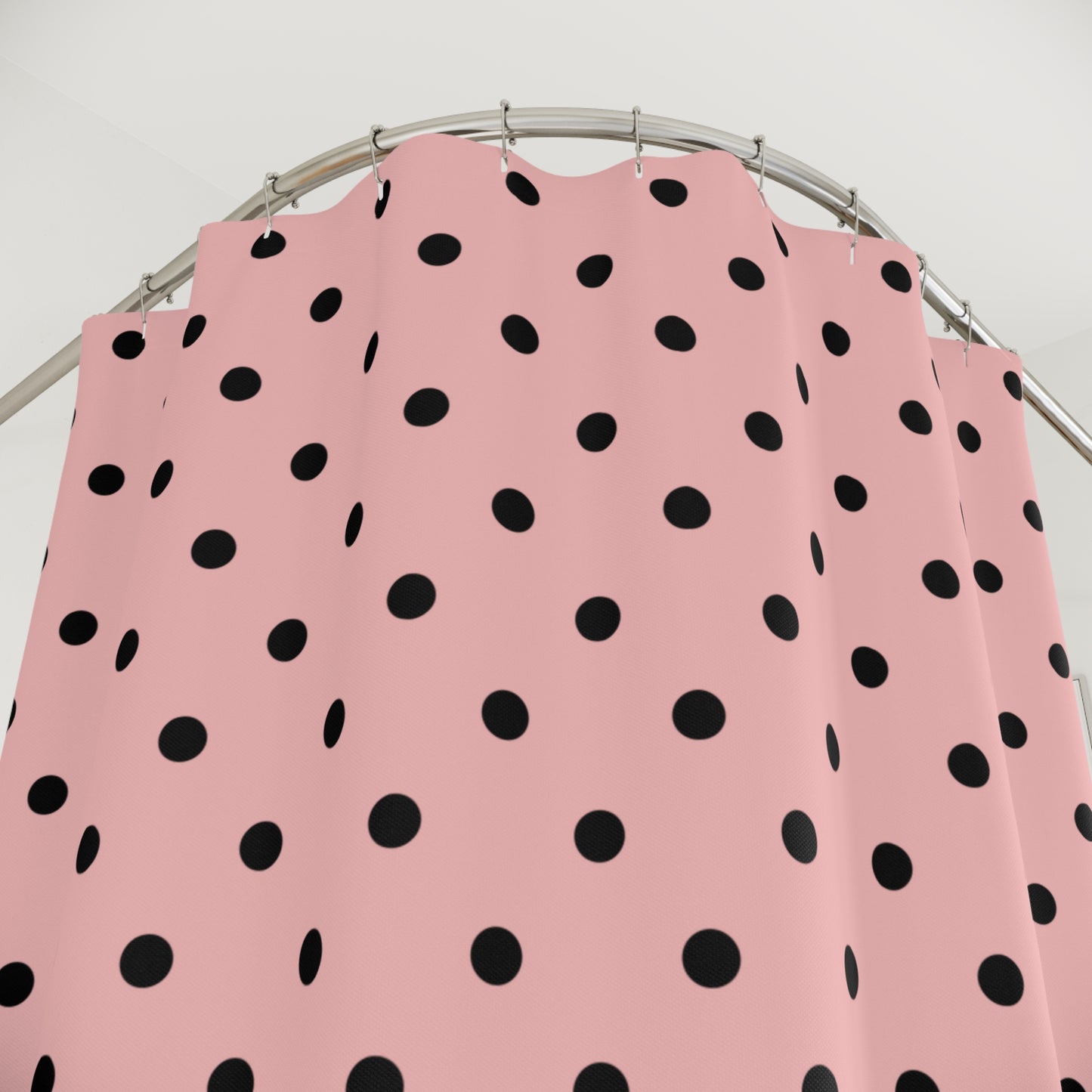 Pink apron with black polka dots on a metal stand against a white background
