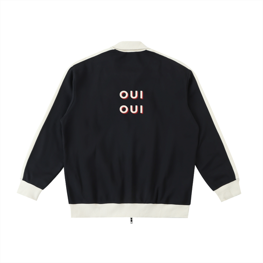 The back of a black bomber jacket with cream ribbed trim and cuffs, featuring the word 'OUI' printed in white with a red and blue 3D offset effect.