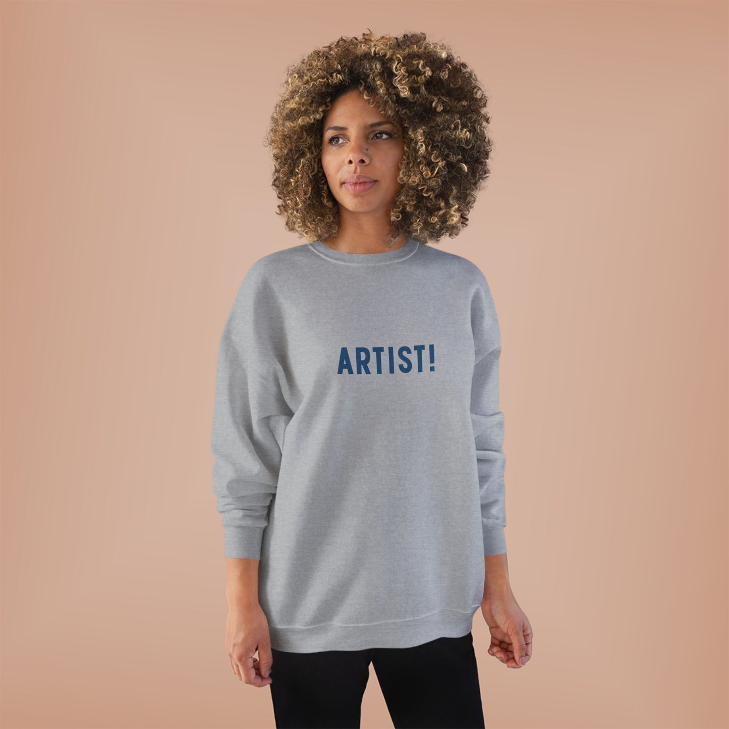 Woman wearing a gray sweatshirt with 'ARTIST!' text on a beige background