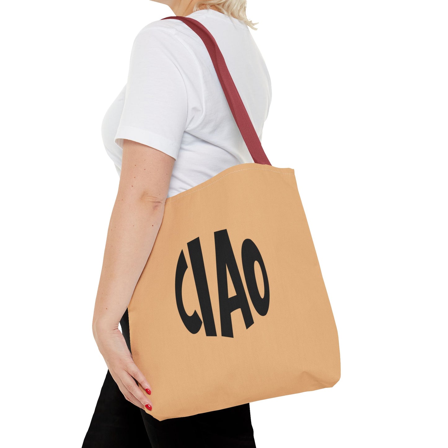 Person holding a tan tote bag with 'CIAO' printed on it against a white background