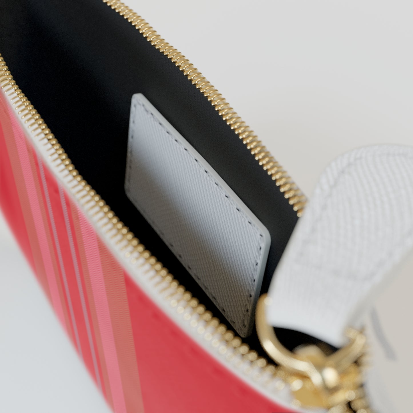 Close-up of a red handbag with gold zipper and white interior.