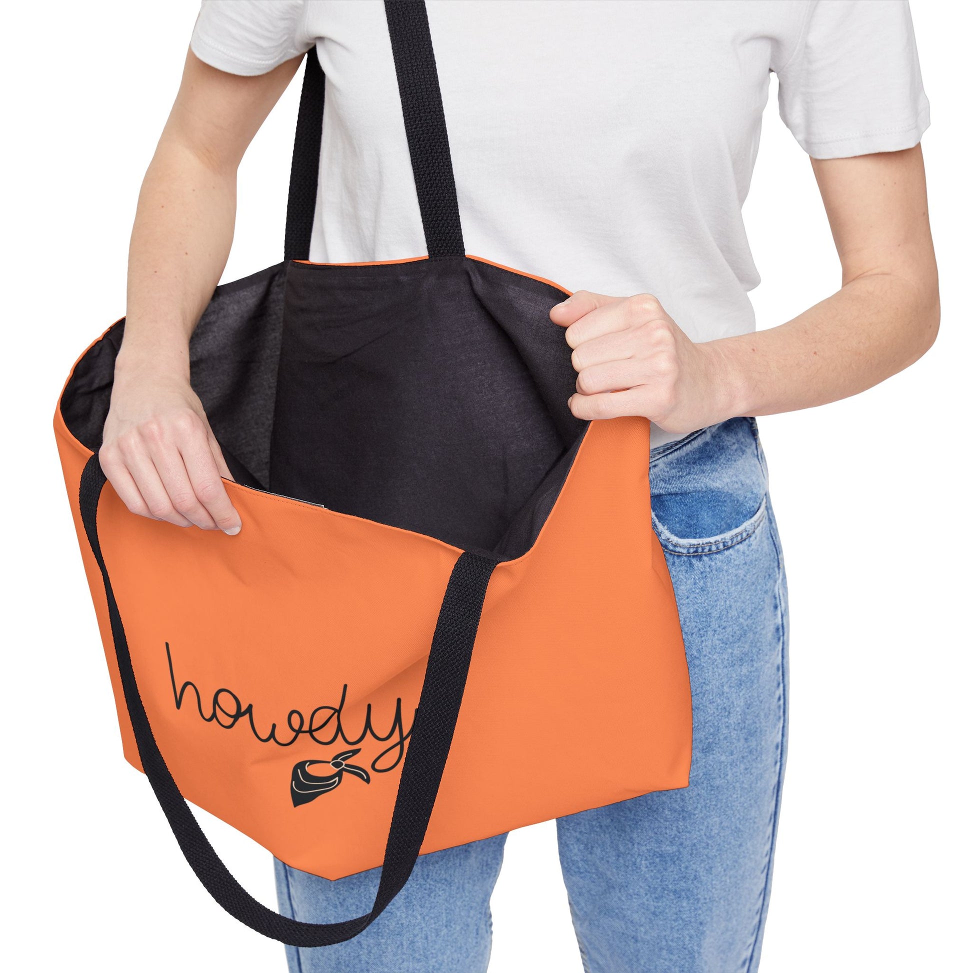 Person holding an orange and black tote bag with 'howdy' text.