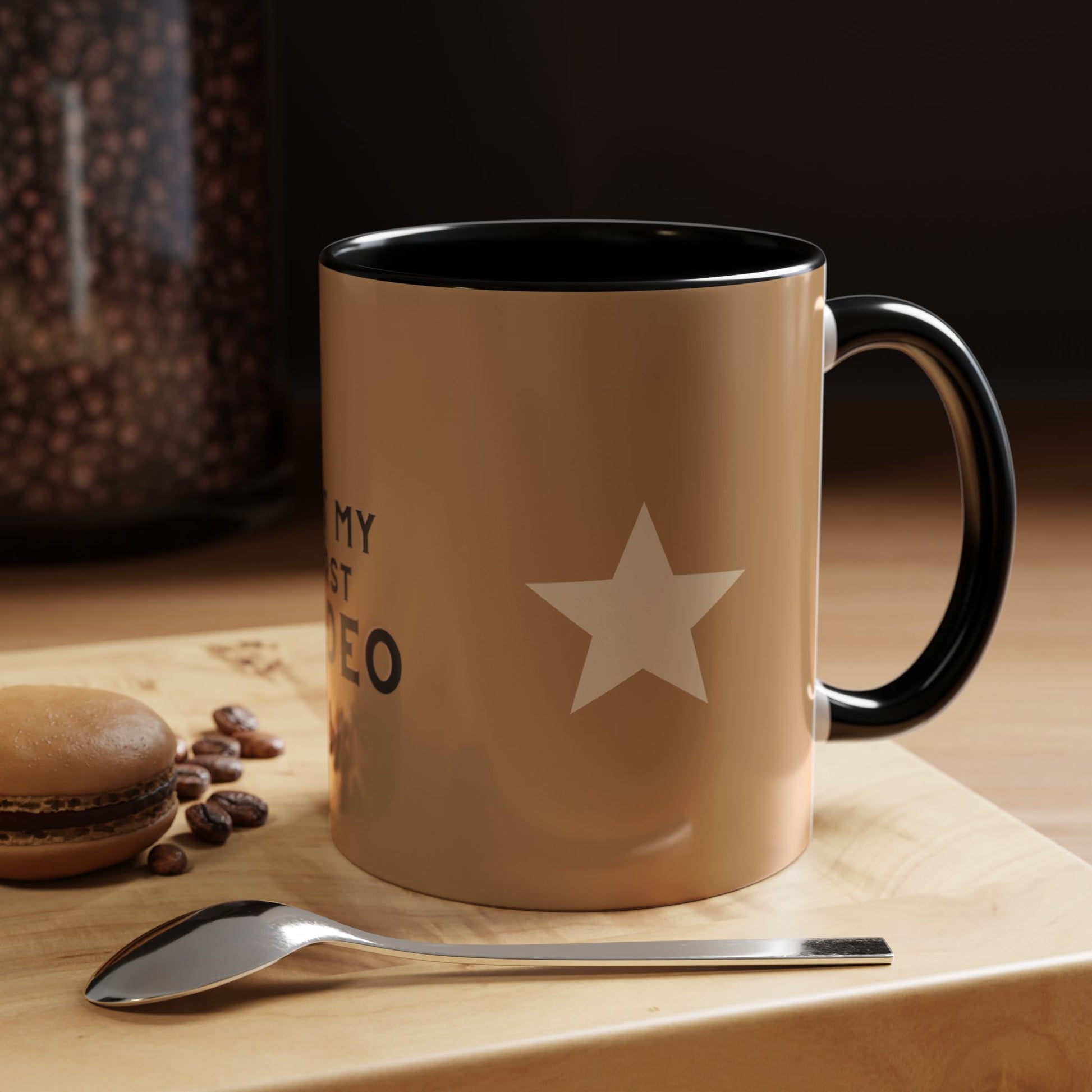 Brown mug with star design and text, placed on a wooden surface with coffee beans and a spoon.