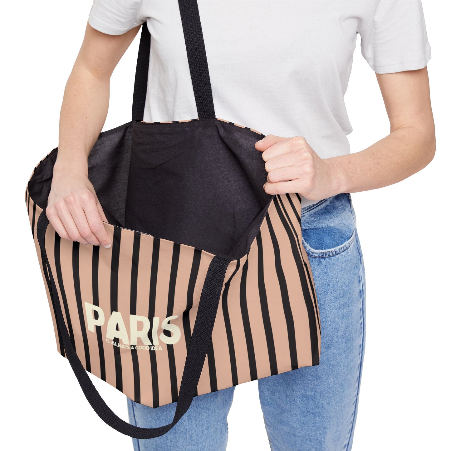 Person holding a striped tote bag with 'Paris' text on a white background