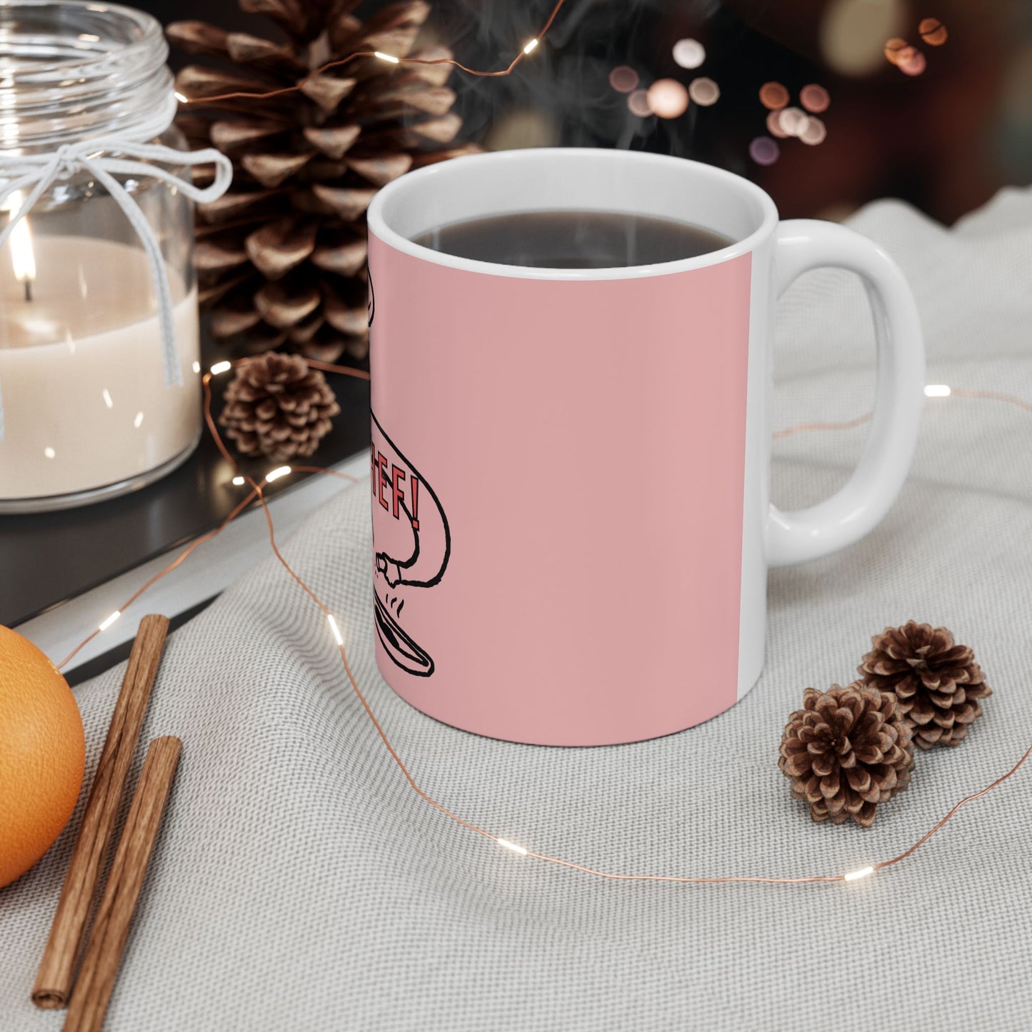 Pink mug with a logo on a table with decorative items