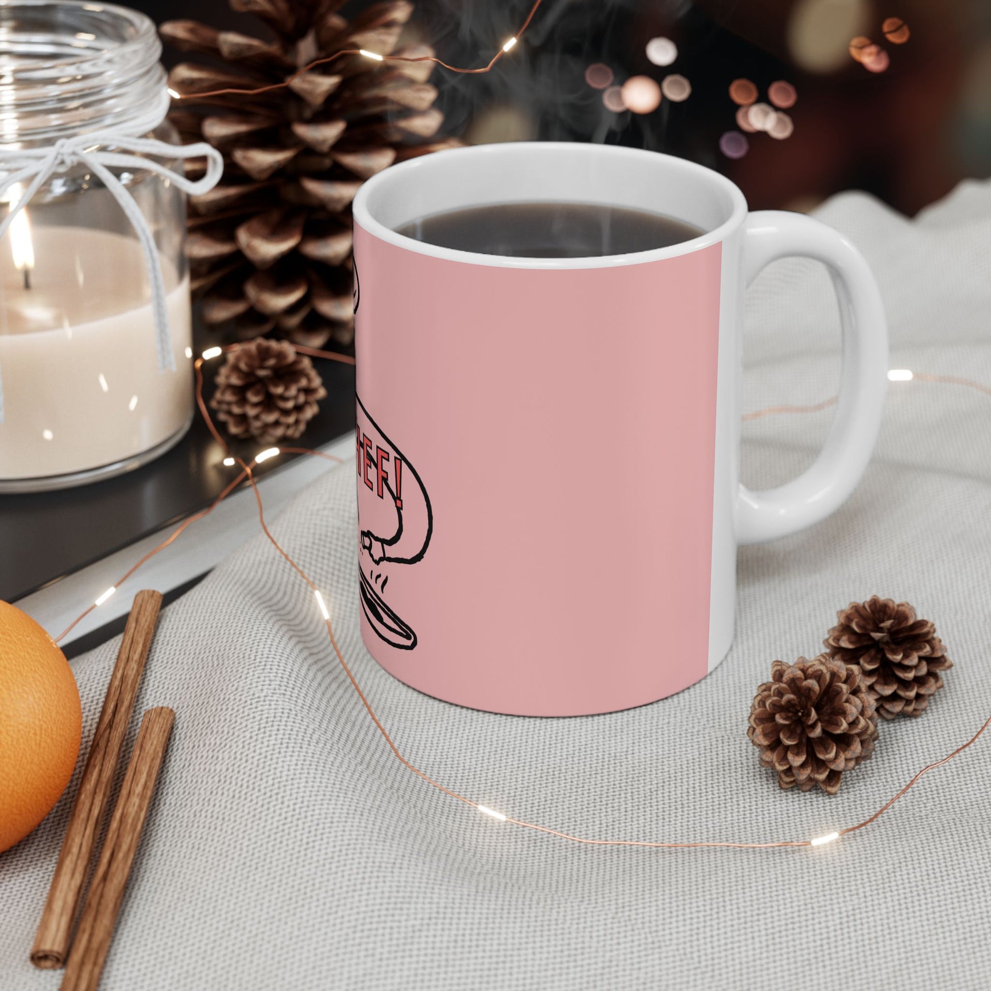 Pink mug with a logo on a table with decorative items