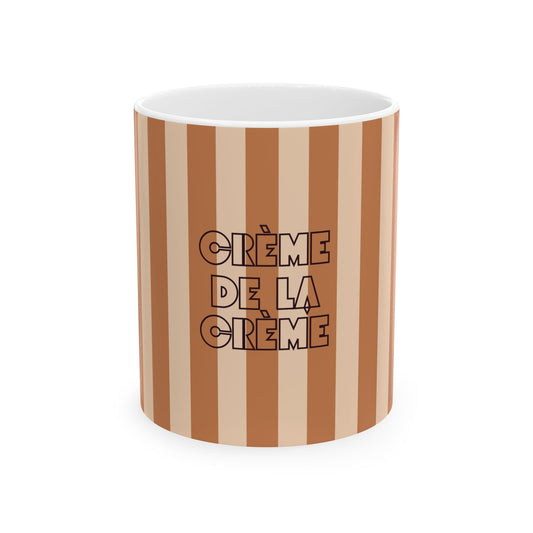A white ceramic mug with vertical brown and beige stripes, featuring the French text 'CRÈME DE LA CRÈME' in a black outlined typographic font on the front.