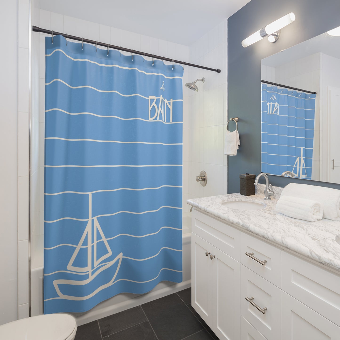 Bathroom with blue shower curtain featuring sailboat design and white cabinets.