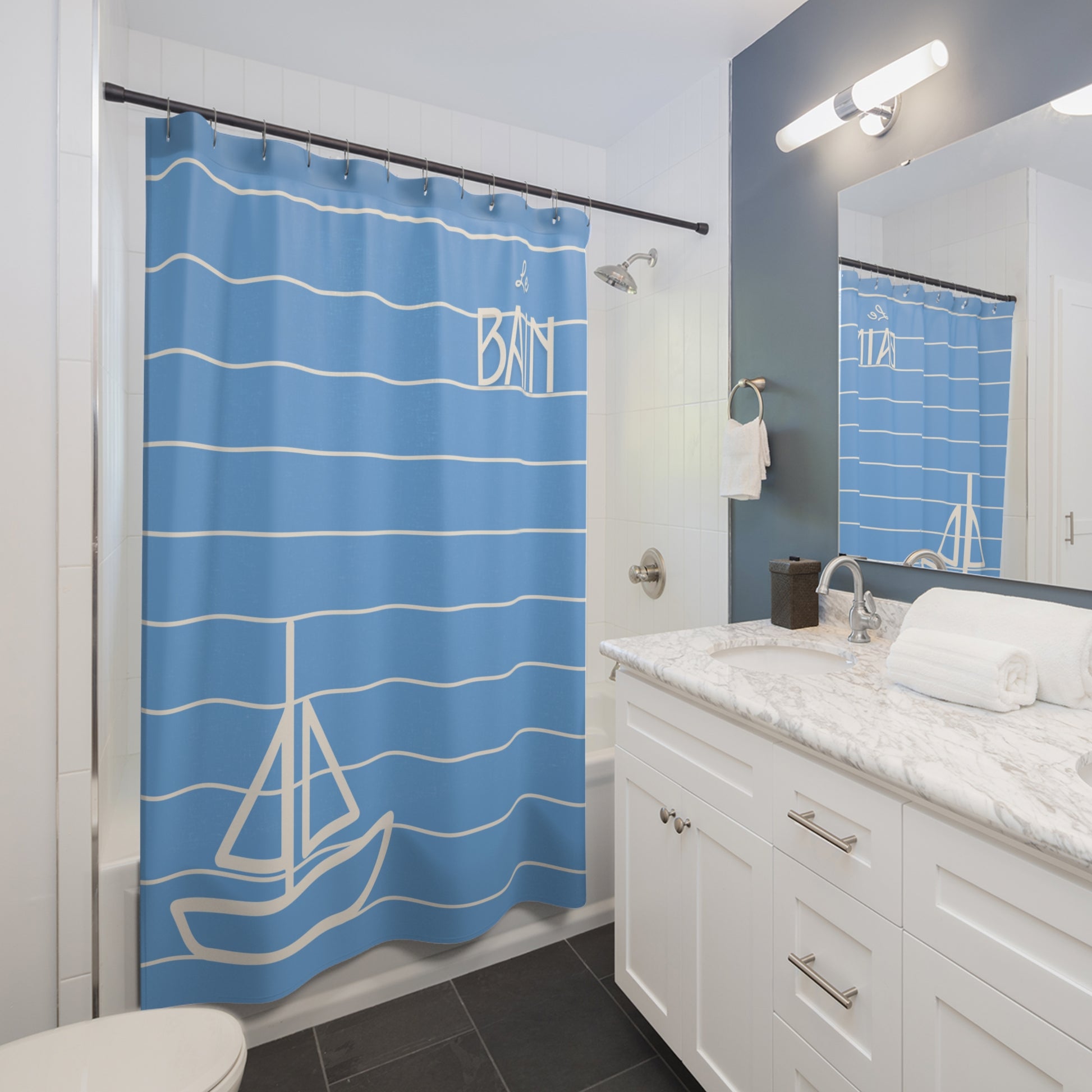 Bathroom with blue shower curtain featuring sailboat design and white cabinets.