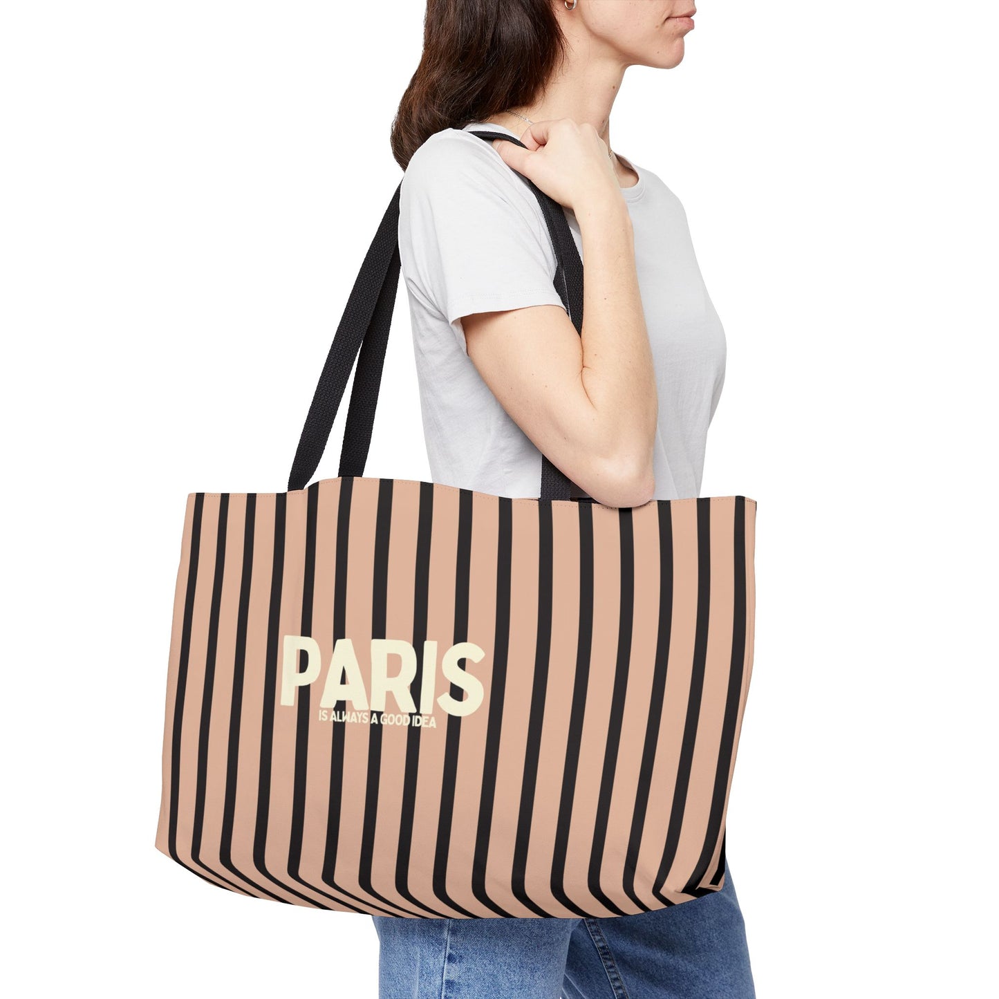 Person holding a striped tote bag with 'PARIS' text on a white background
