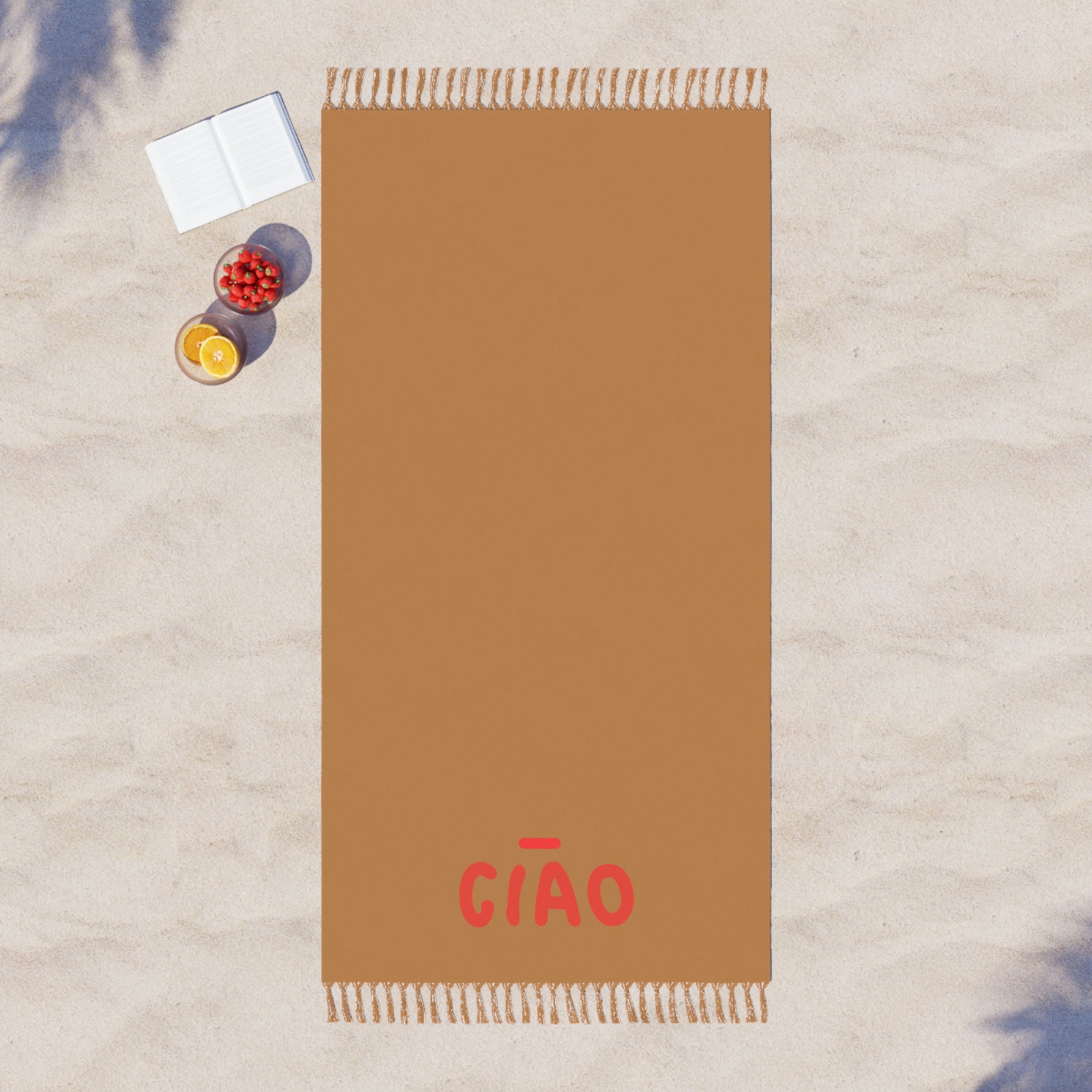Brown towel with 'GIAO' branding on a textured surface with a book and fruit.