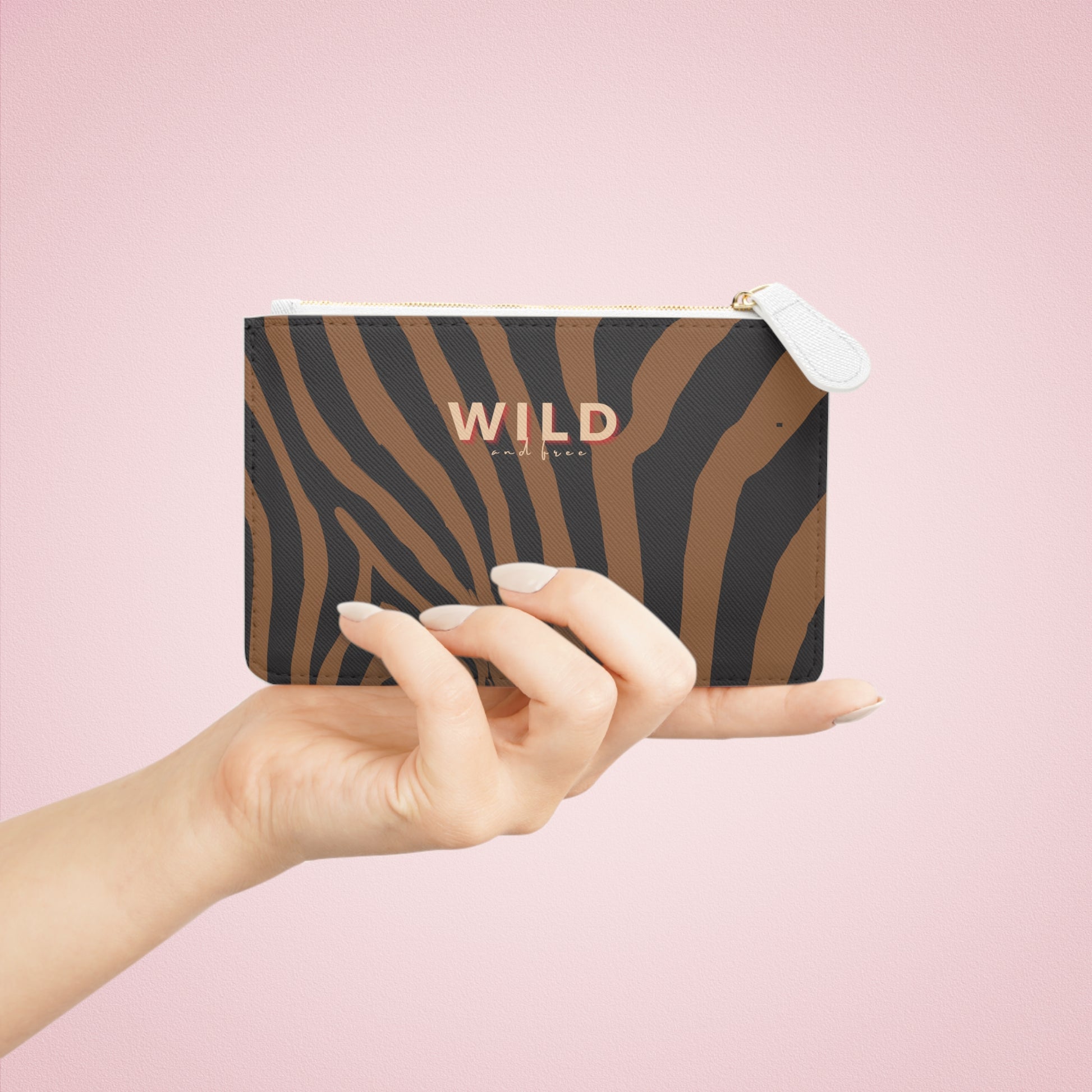 Hand holding a zebra-striped pouch with 'WILD' branding on a pink background