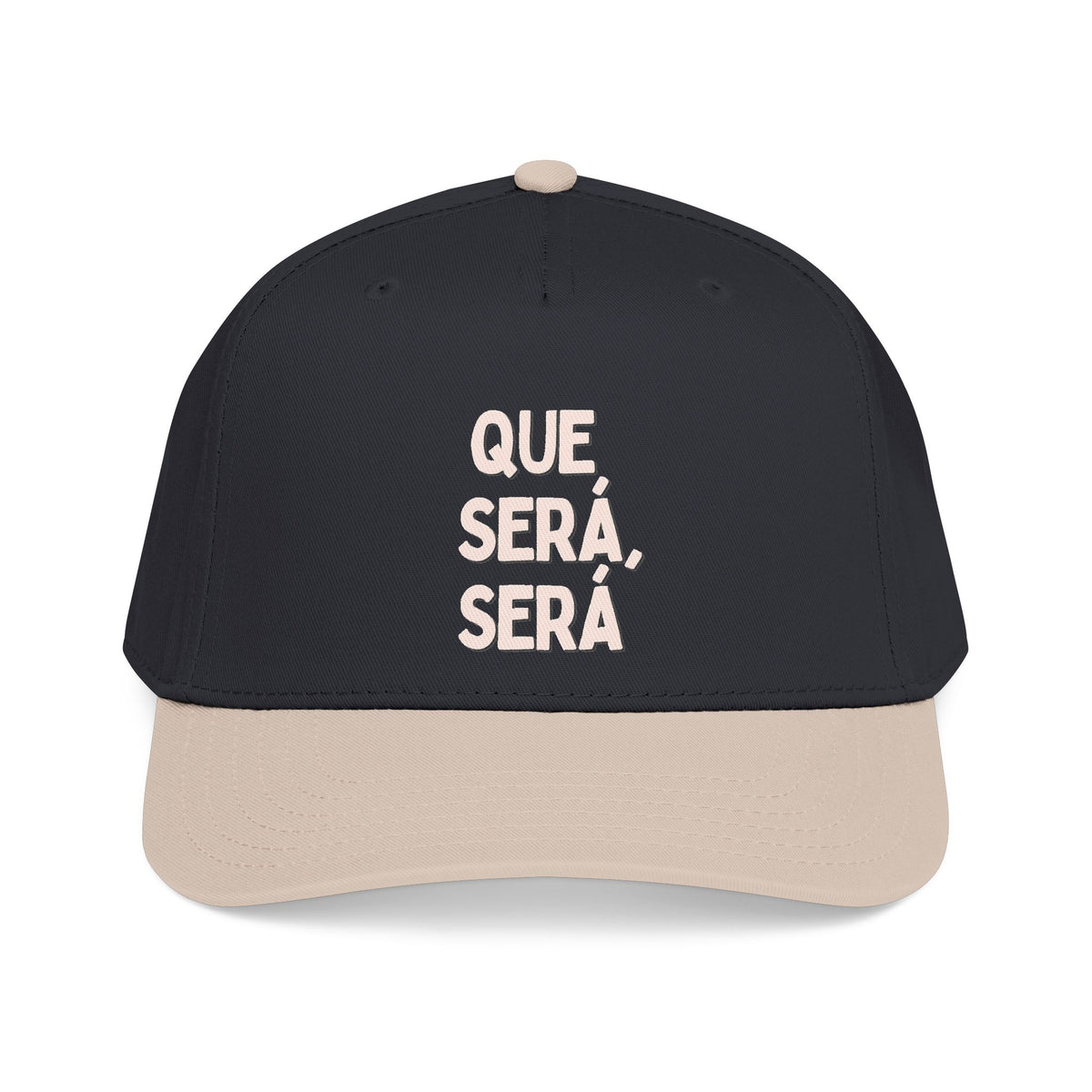 A structured baseball cap with a black crown and a light beige visor, featuring the Spanish text 'QUE, SERÁ, SERÁ' printed in beige on the front.