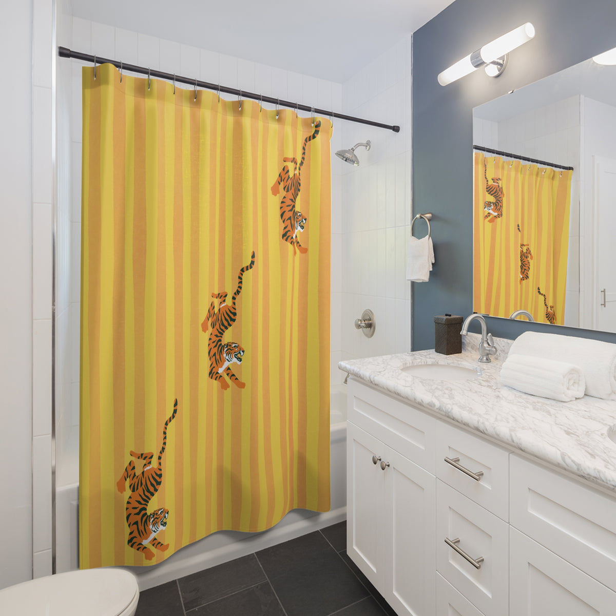 A yellow striped shower curtain with illustrations of leaping tigers hanging from a black rod in a modern white and blue bathroom.