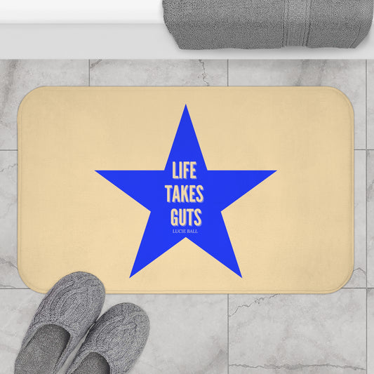 Beige doormat with a blue star and 'Life Takes Guts' text on a marble floor.