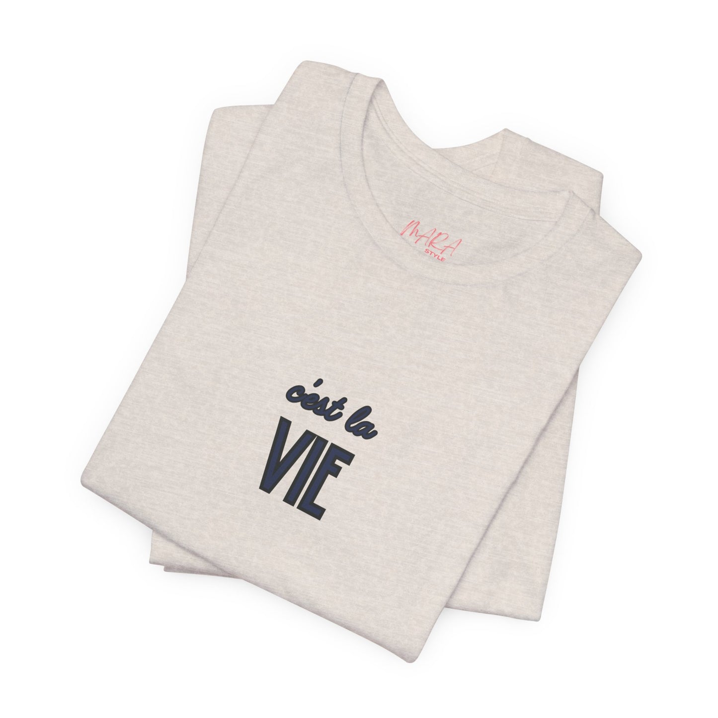 Folded beige tank top with 'c'est la vie' text on a white background