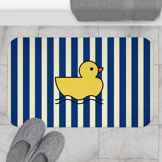 Bath mat with a yellow rubber duck on a blue and white striped background, placed on a tiled bathroom floor.